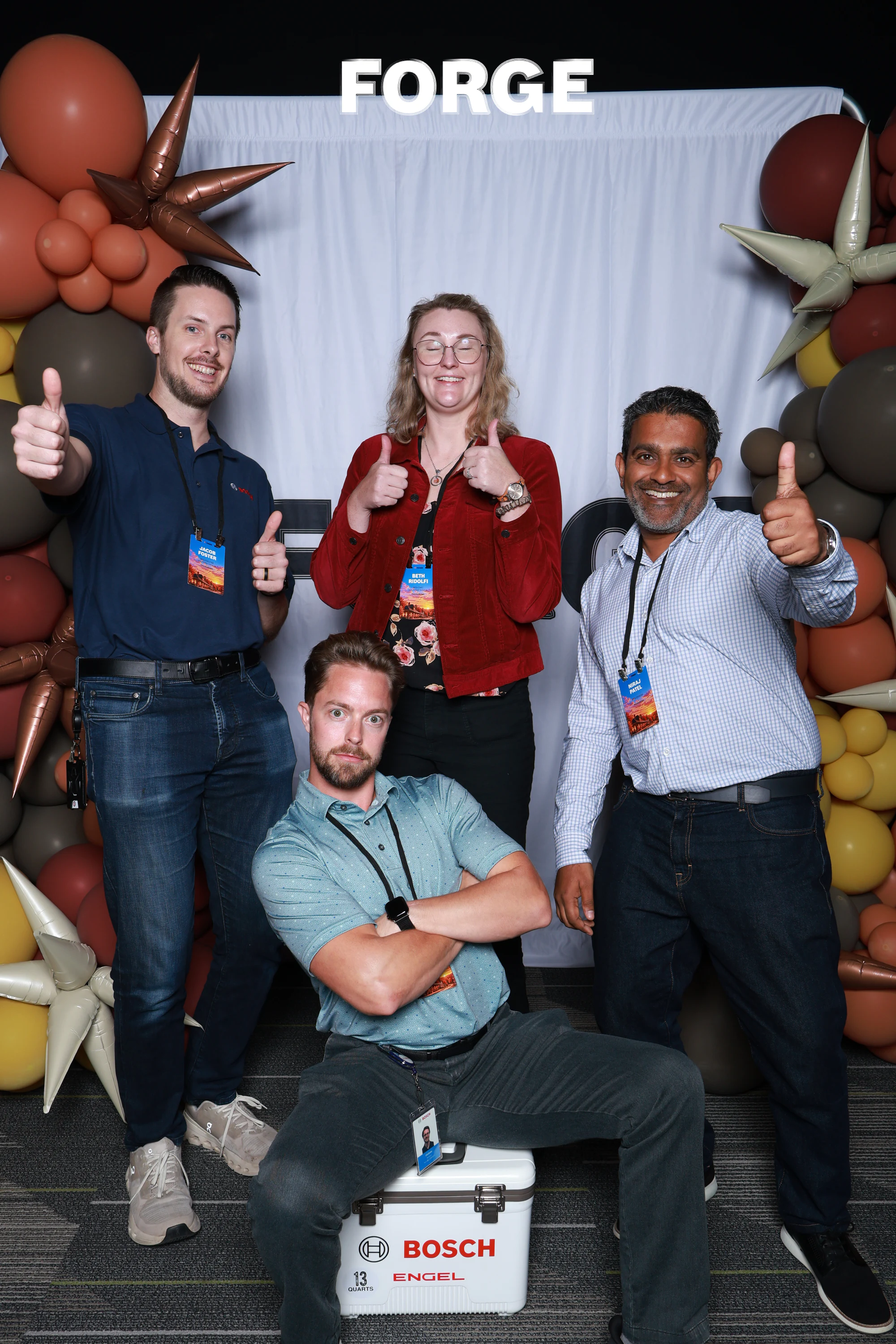 Four guests giving thumbs up, one crouched on a Bosch cooler at Bosch FORGE 2026
