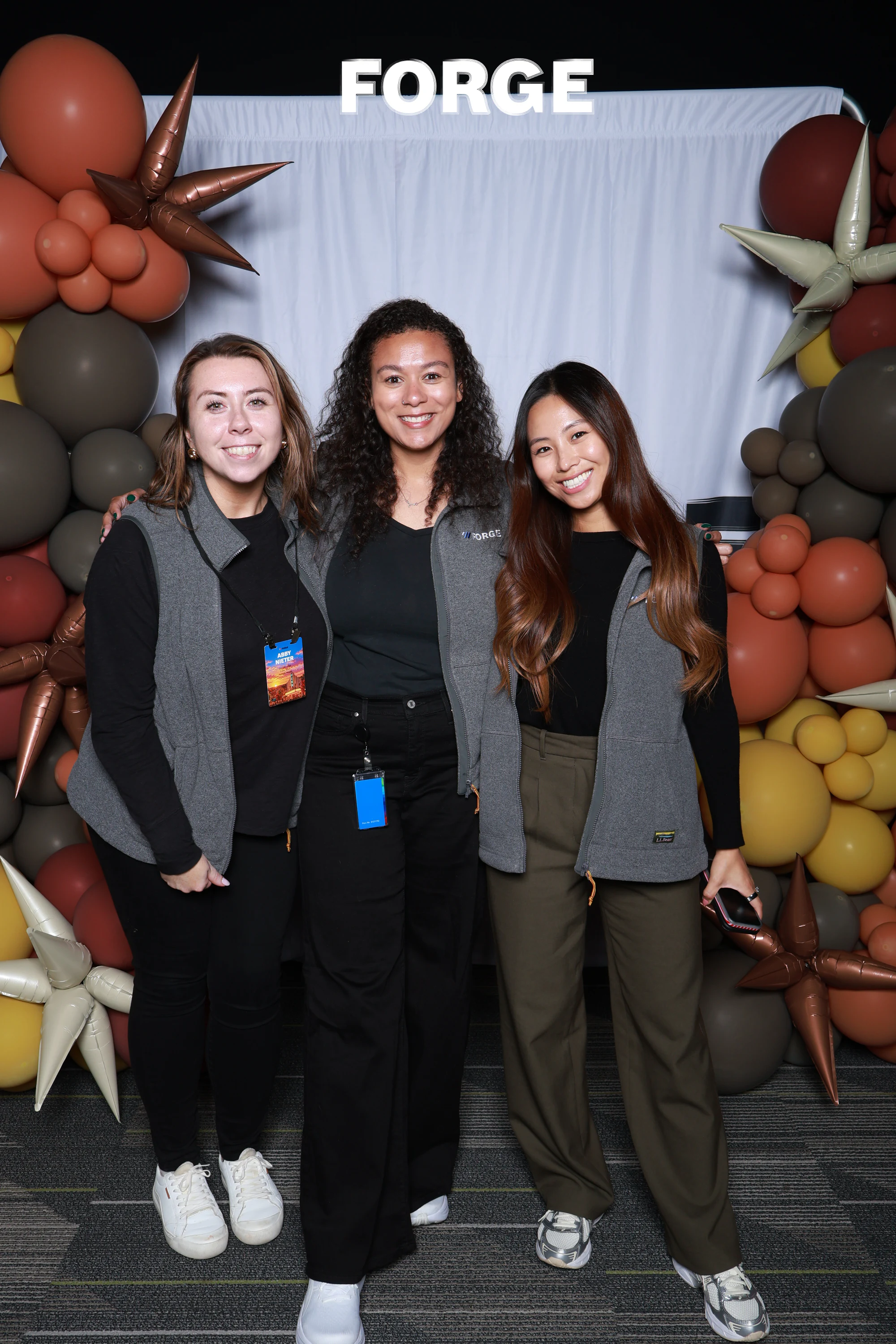 Three women in grey vests side by side in front of the FORGE drape at Bosch FORGE 2026