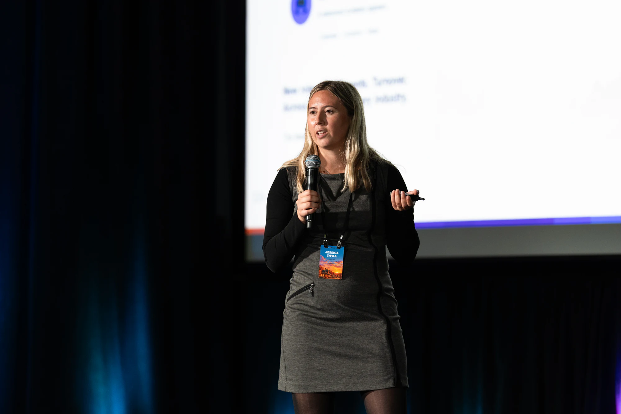 A presenter in a grey dress pitching with a mic in front of the screen at Bosch FORGE 2026