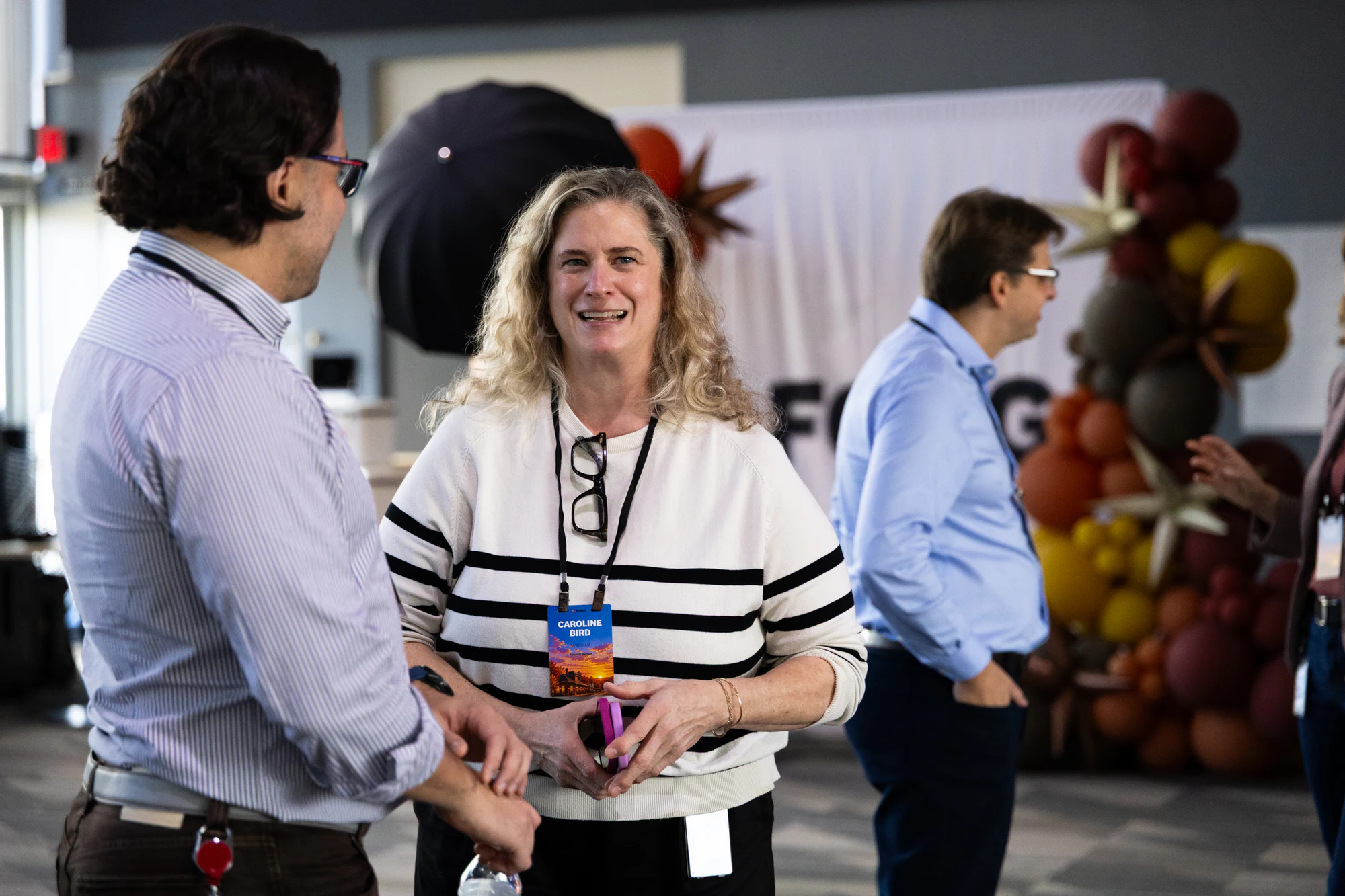 A woman in a striped sweater laughing with colleagues in the marketplace at Bosch FORGE 2026