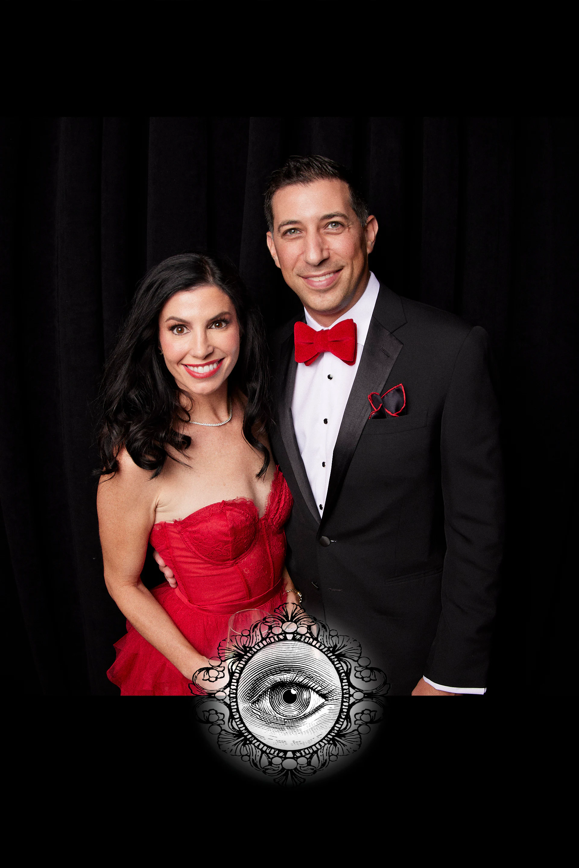 A guest in a red gown and a guest in a tuxedo and red bow tie at the carnivalesque wedding at the Fisher Building