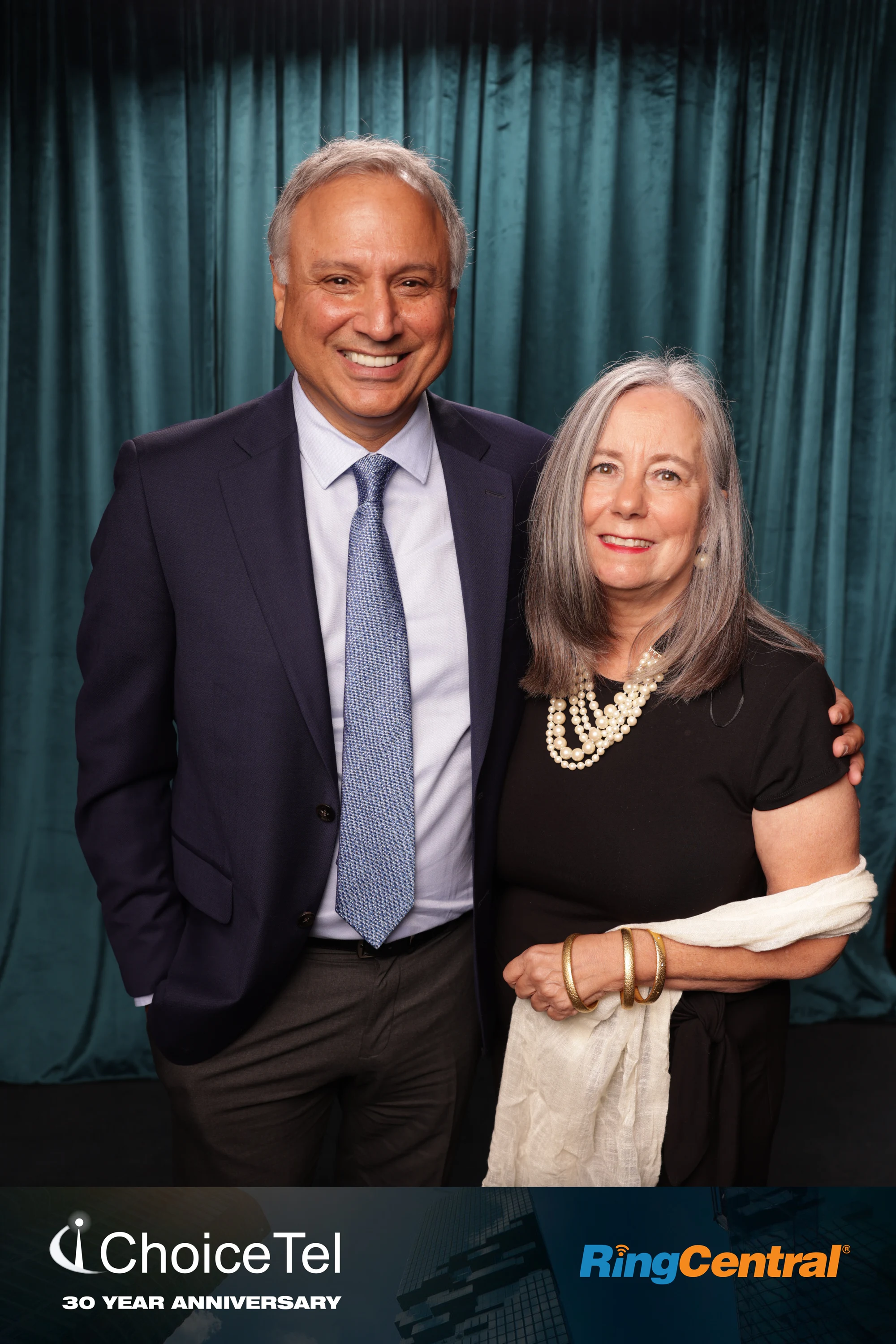 A couple, him in a navy suit and blue tie, her in black with pearls, at ChoiceTel 30 Year Anniversary at The Whitney