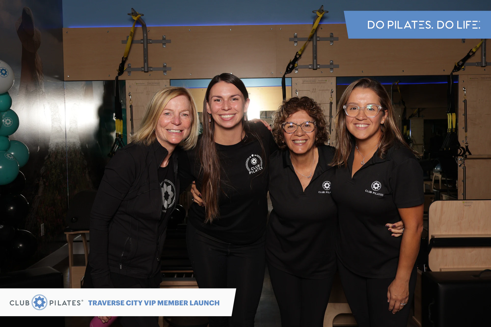 Four women in black Club Pilates shirts standing in a row with reformers behind them at Club Pilates Traverse City