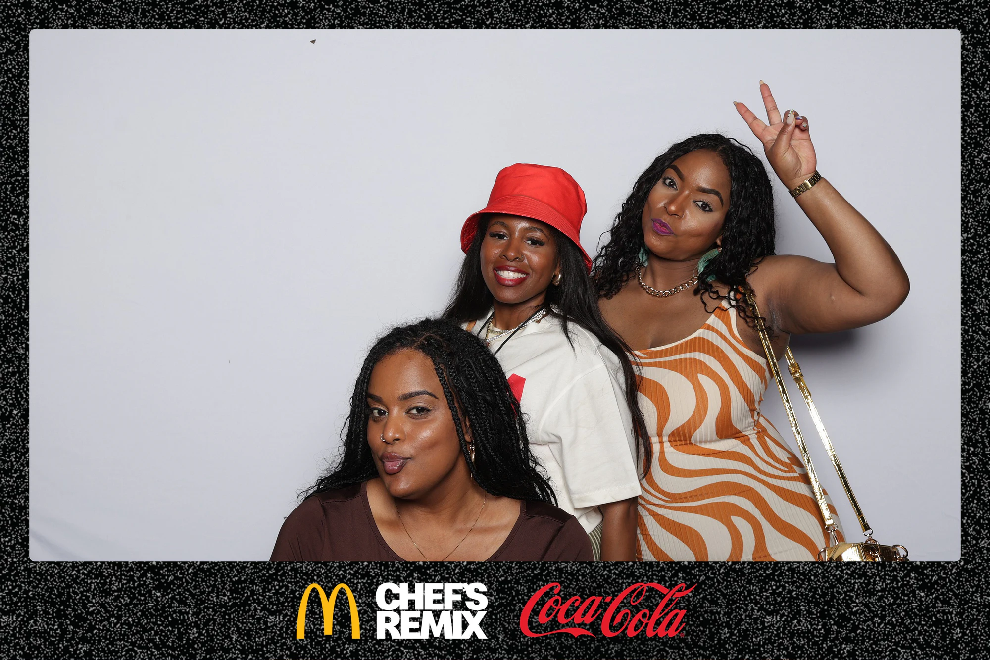Three guests, one in a red bucket hat, one crouched in front at Coca-Cola x McDonald’s at the Jerk x Jollof Afterparty
