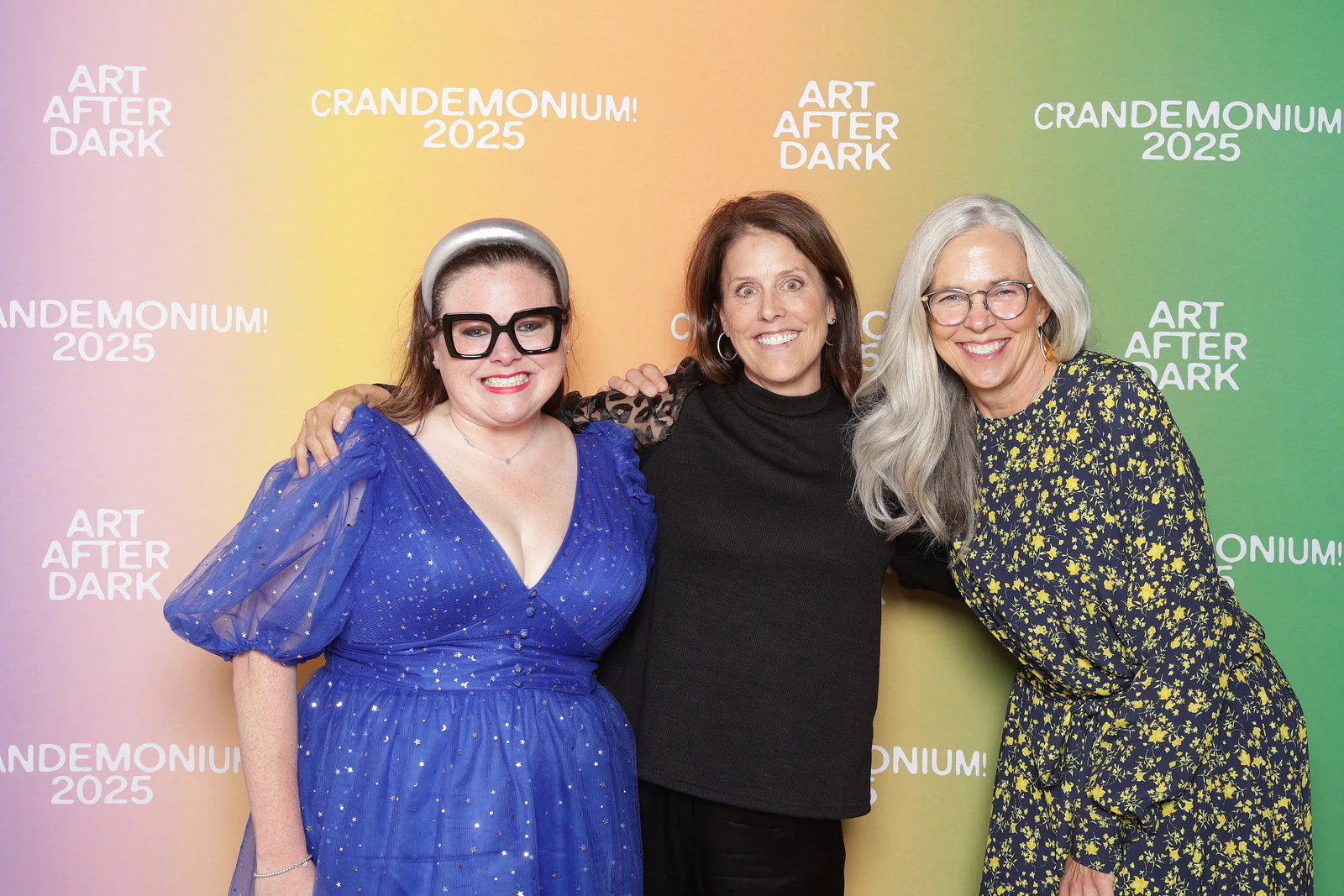 The three women arm in arm, smiling at Crandemonium 2025