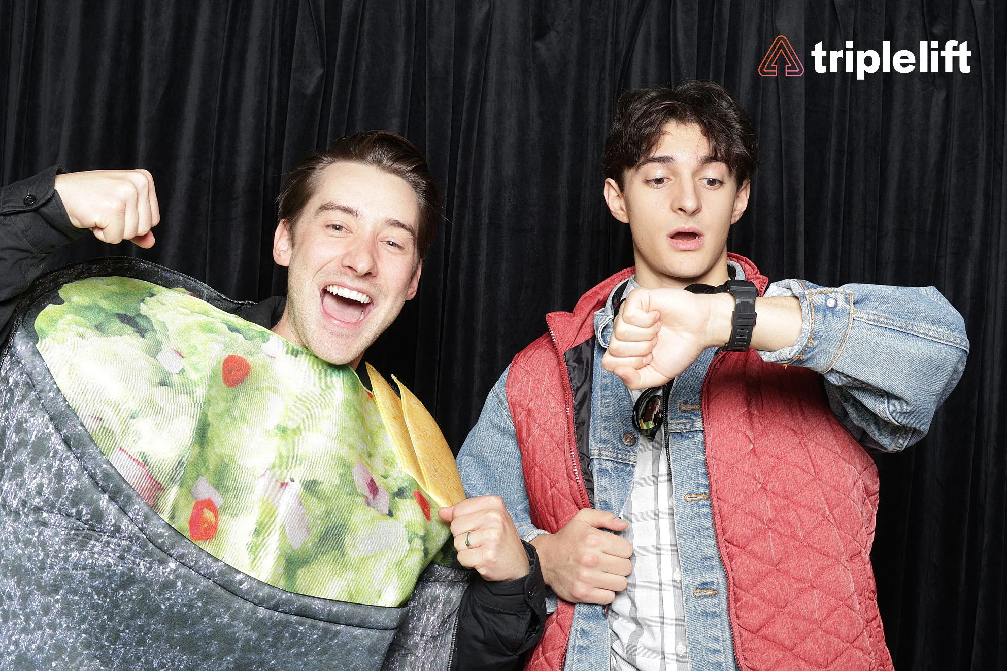Two men, one in a burrito costume flexing an arm and laughing, one in a red quilted vest and denim jacket checking his watch at TripleLift Halloween Party