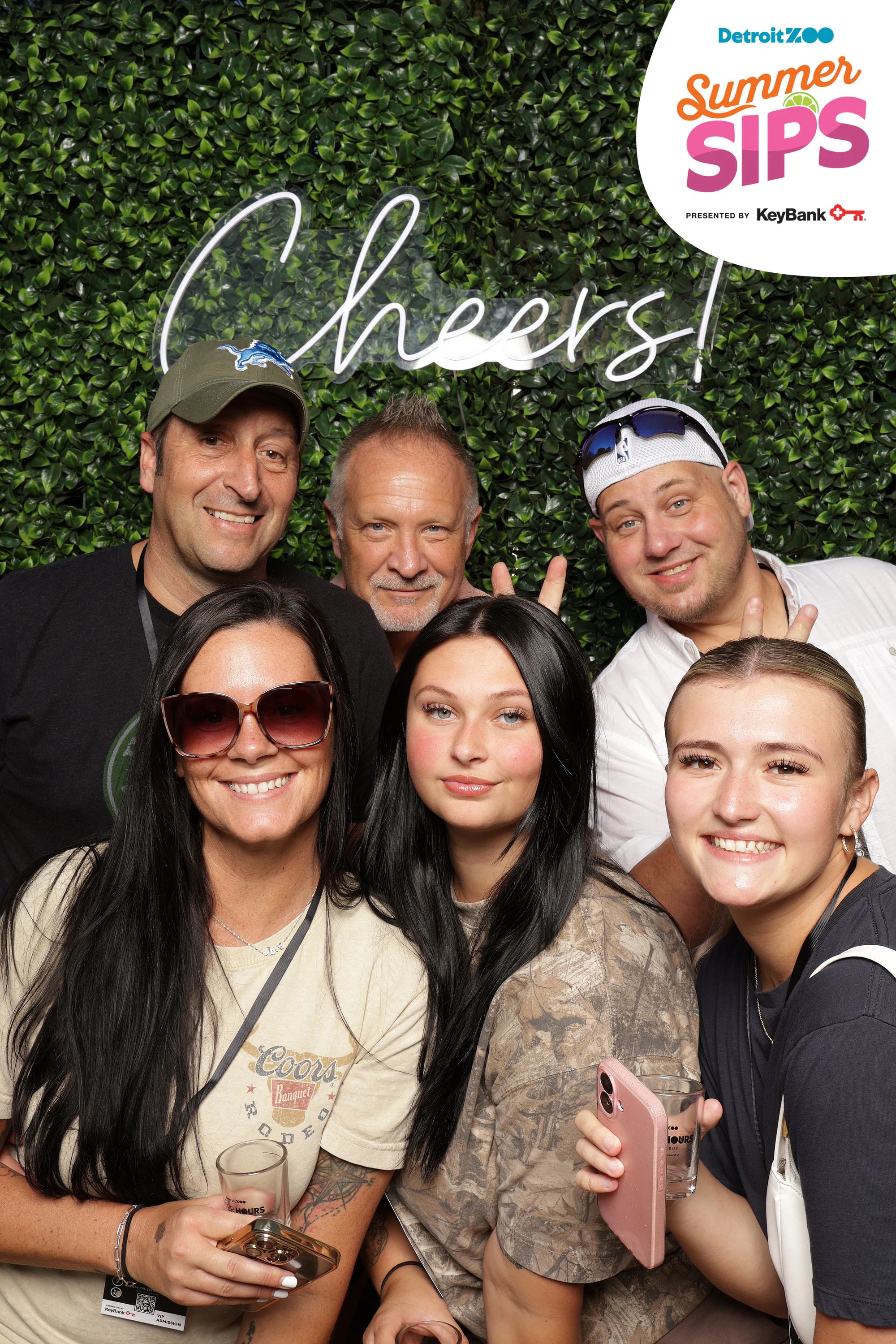 Six friends stacked on the hedge wall, sunglasses and drinks at Detroit Zoo Event Series