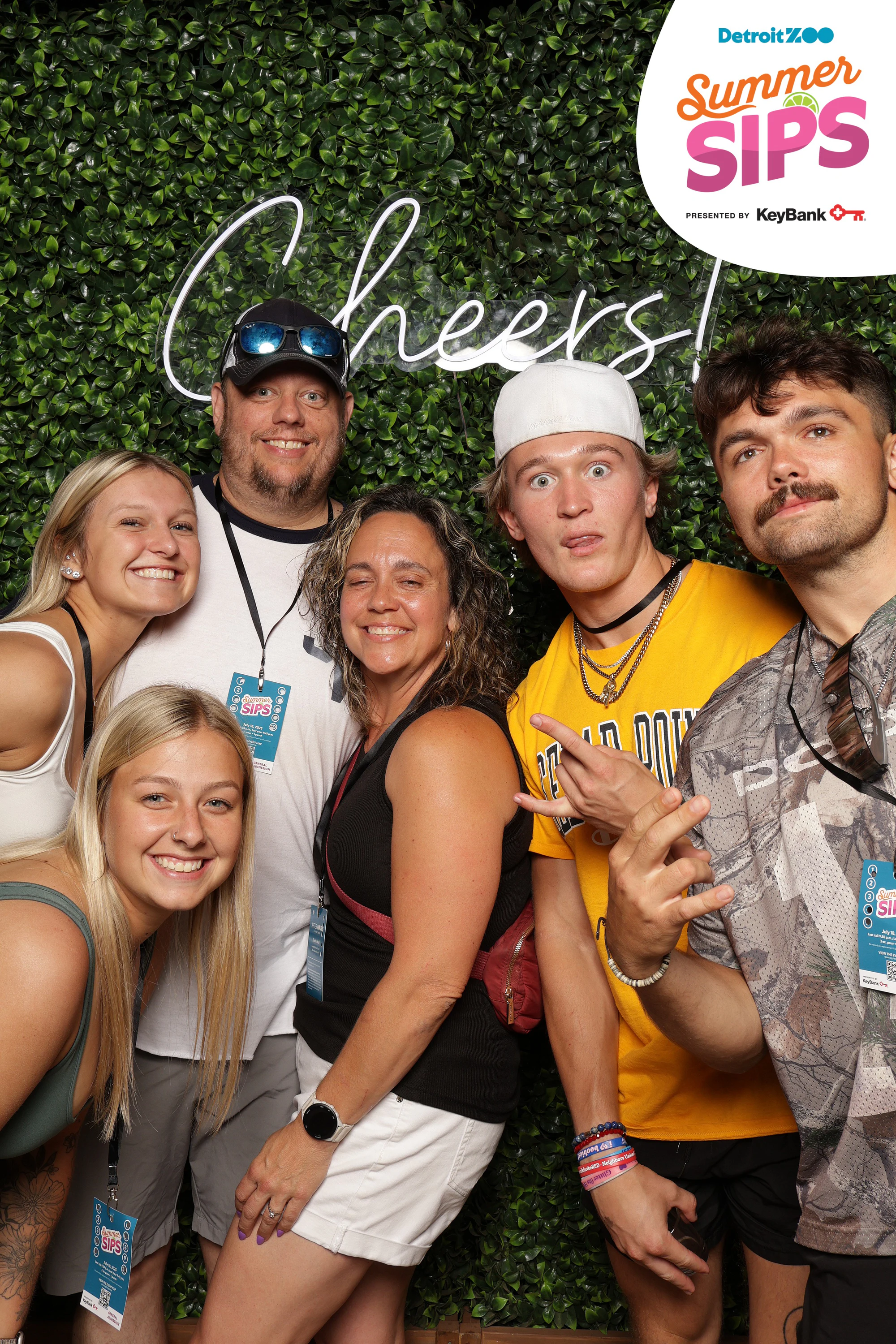 Six deep against the greenery, everyone smiling at Detroit Zoo Event Series