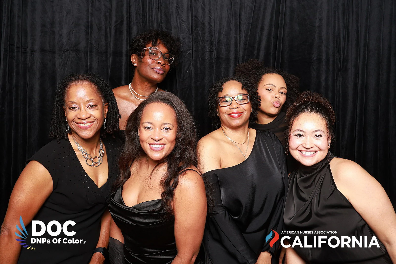 The seven women smiling, one at the back blowing a kiss at DNPs of Color