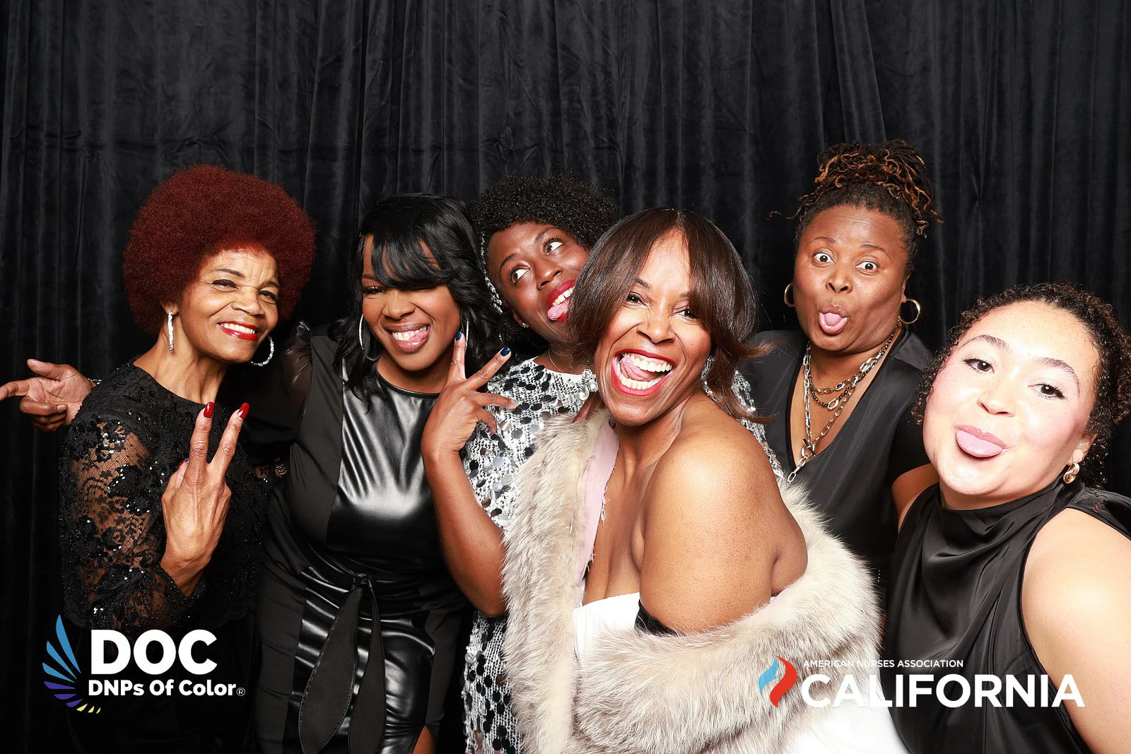 Seven women in black, silver and white posing in front of the black drape at DNPs of Color