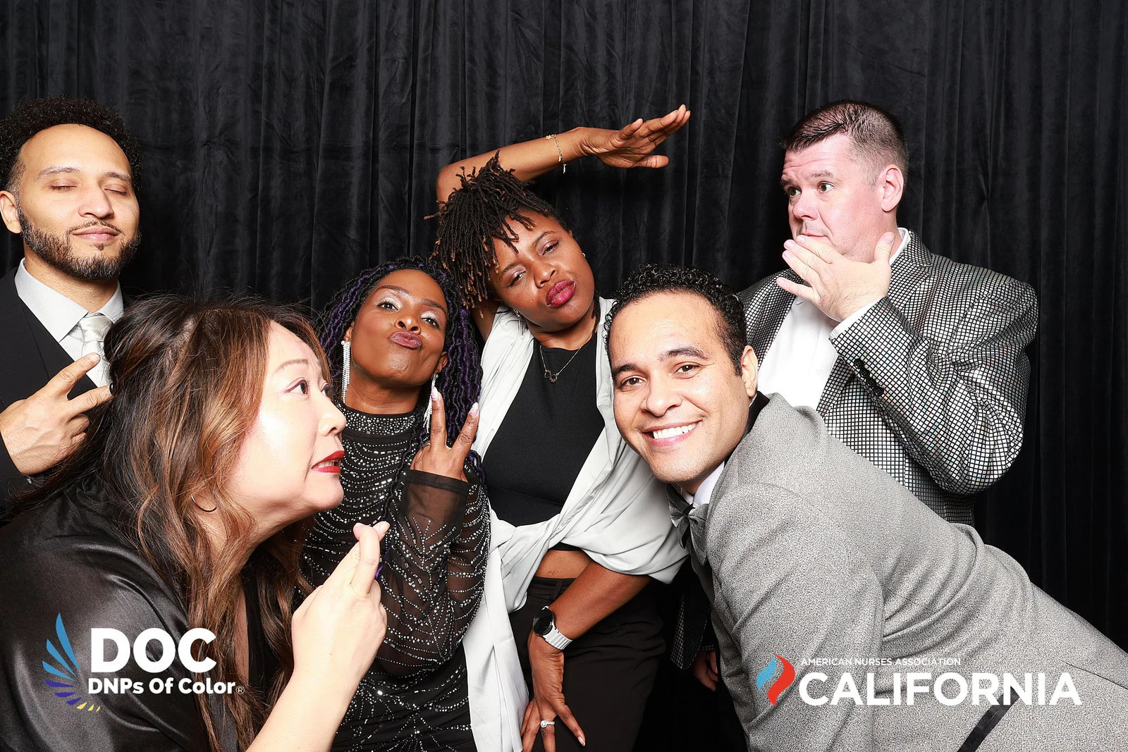 Seven guests in black and silver clowning, one striking a pose with a hand on his chin at DNPs of Color