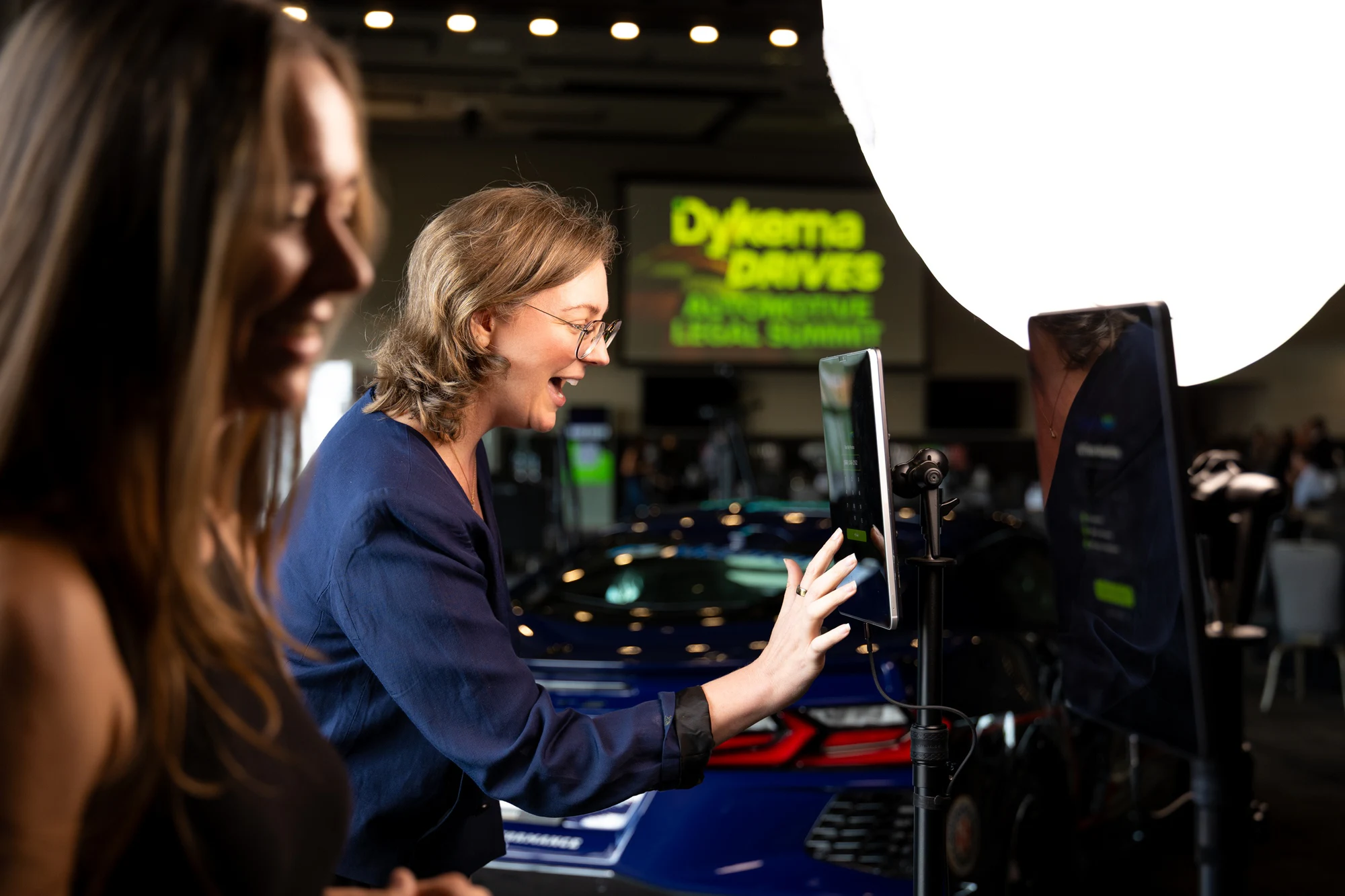 A guest laughing at her AI Time Machine result on the tablet at Dykema Automotive Legal Summit 2026