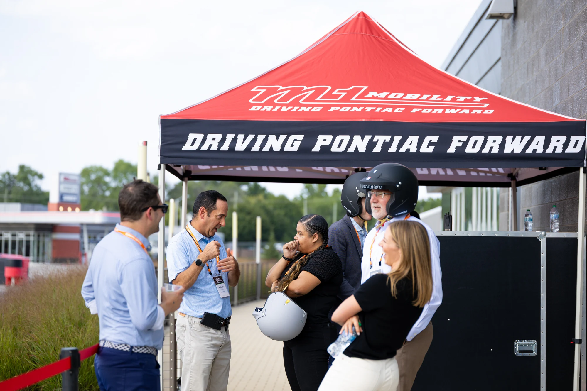 Attendees under the M1 tent picking up helmets at Dykema Automotive Legal Summit 2026