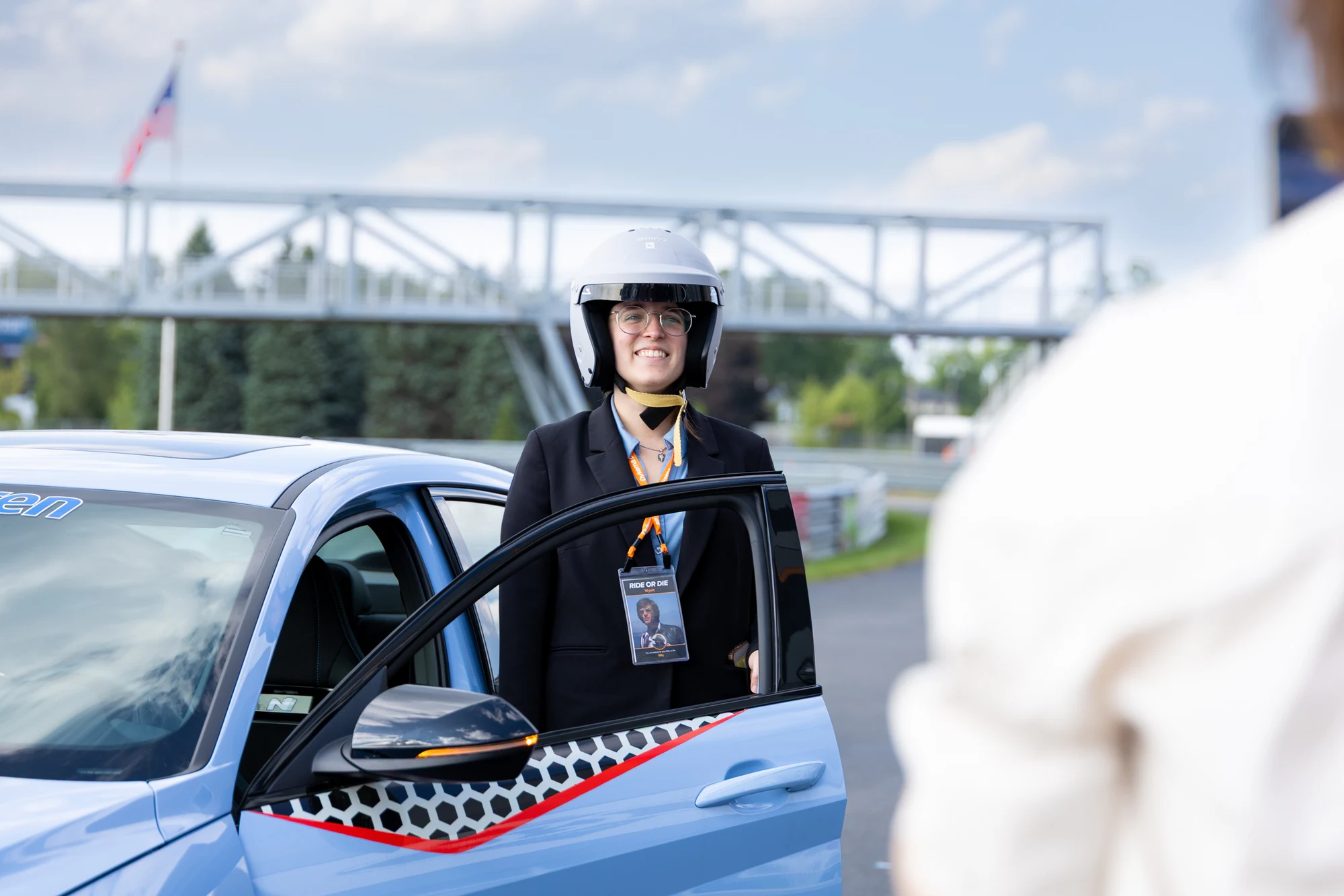 Guest in a helmet at the car door, smiling at Dykema Automotive Legal Summit 2026