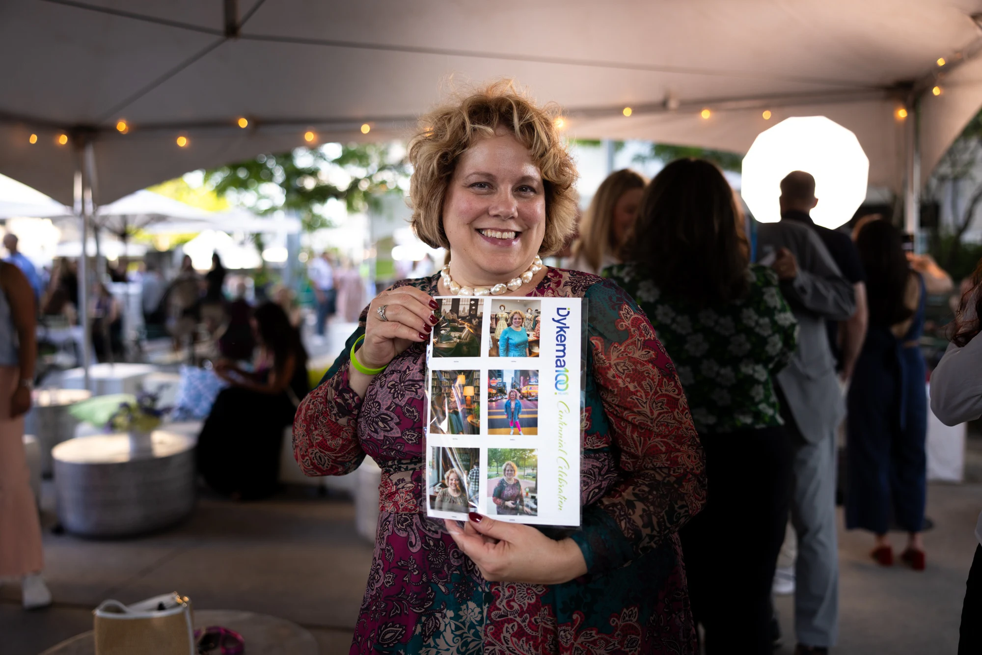A guest holding up her printed AI Time Machine sheet at the Dykema Centennial Celebration