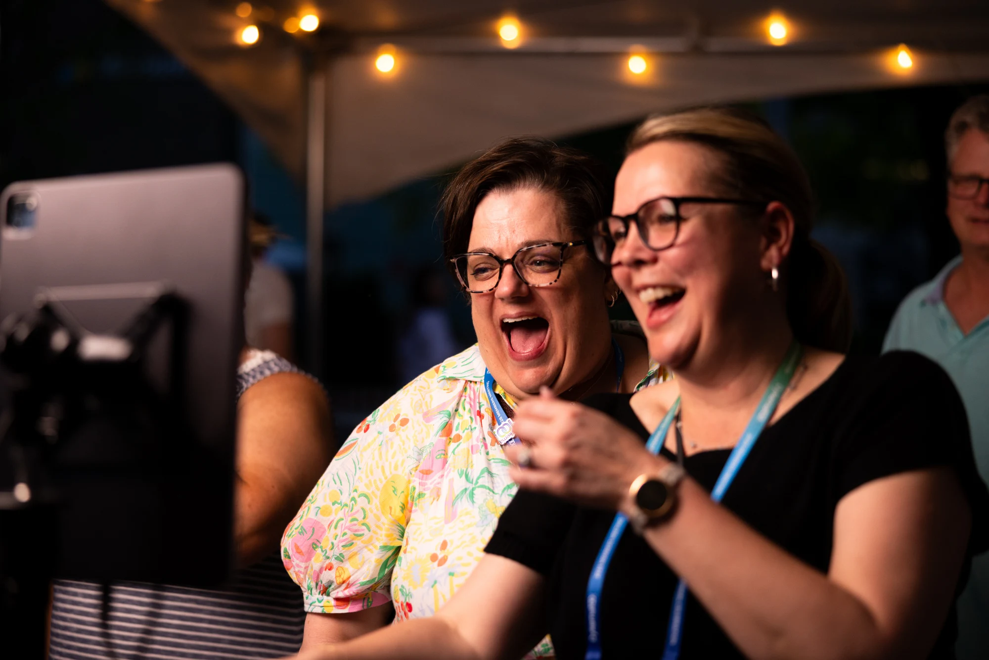Two friends laughing hard at the screen at the Dykema Centennial Celebration