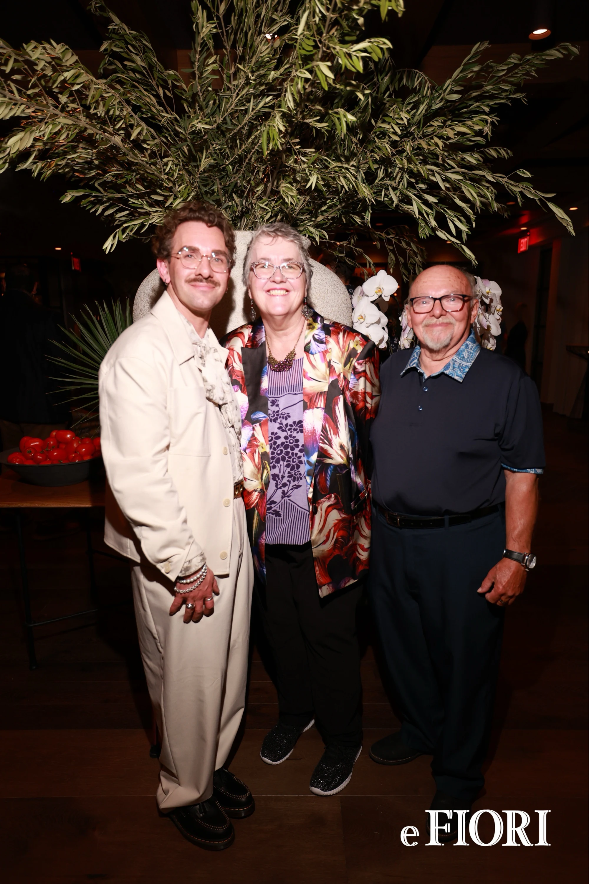 Three guests in front of a tall olive-branch arrangement at e Fiori Birmingham Opening Party