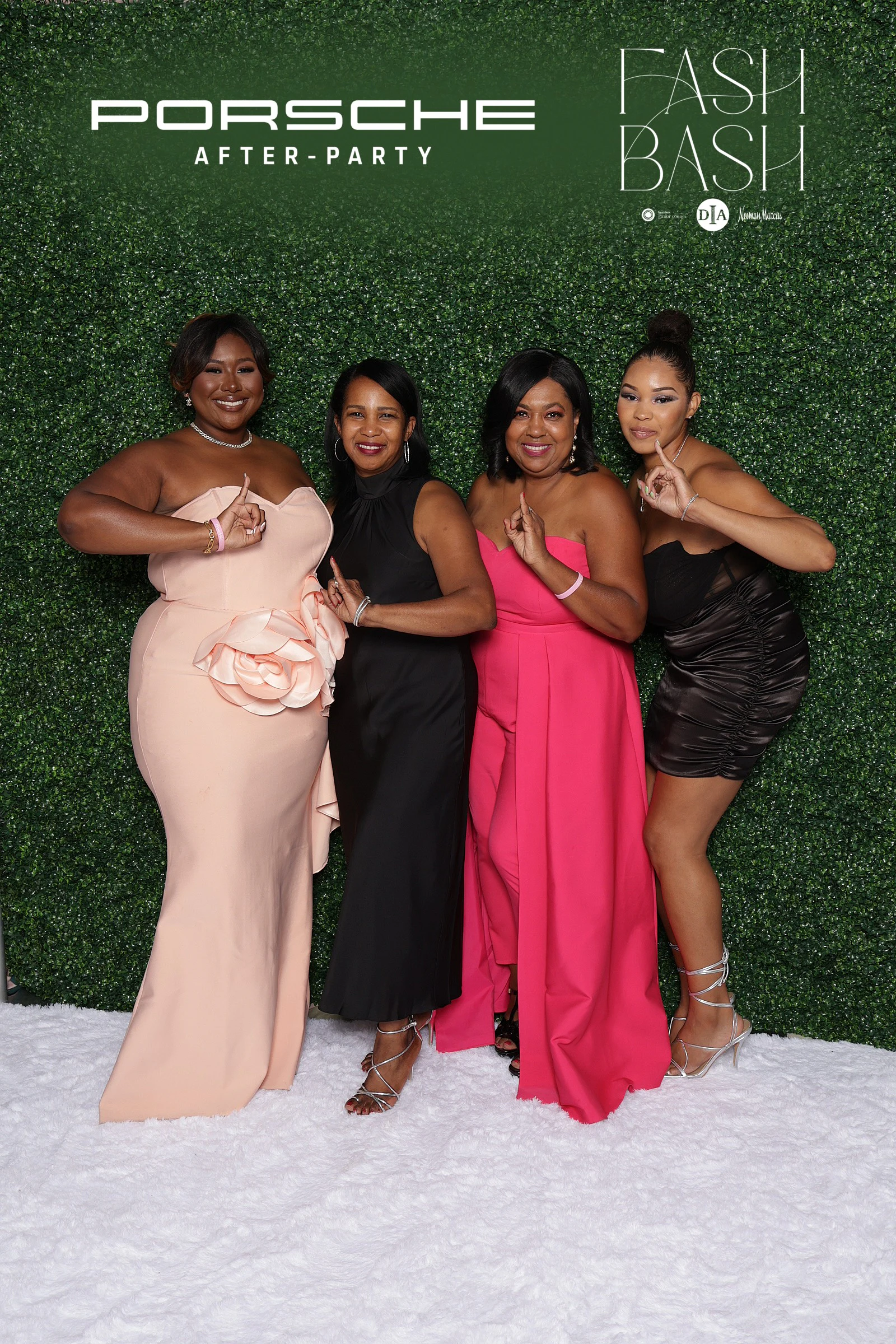 Four women in blush, black and pink throwing hand signs in front of the hedge wall at Fash Bash at the DIA