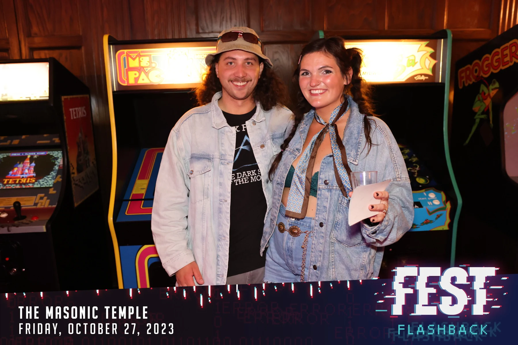 A couple in denim jackets in front of the Ms. Pac-Man and Frogger cabinets at FEST Halloween Party at the Masonic Temple