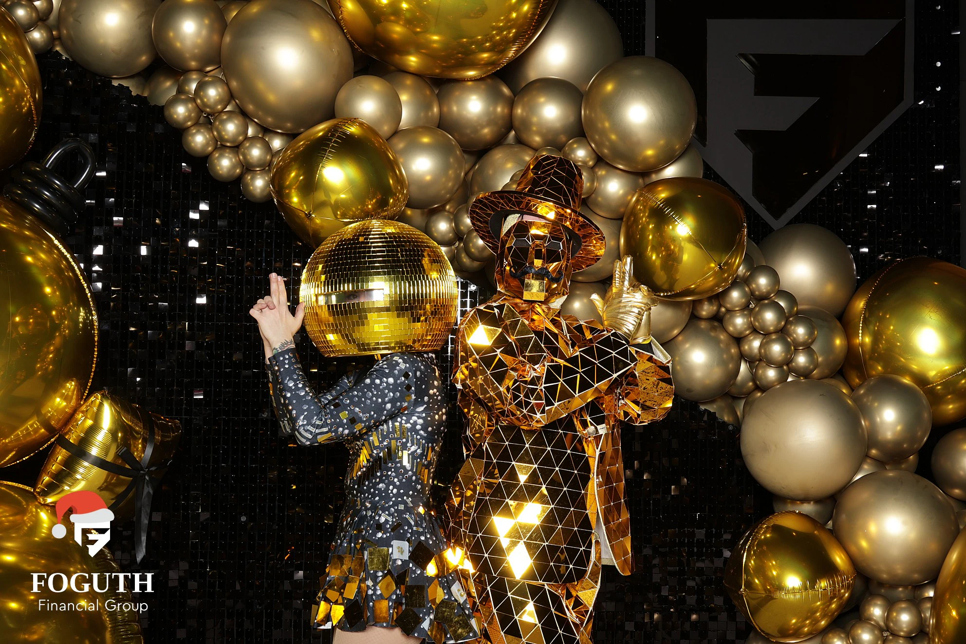 Two performers in mirror-tile costumes, one with a mirror-ball head, striking a pose at Foguth Financial Christmas Party