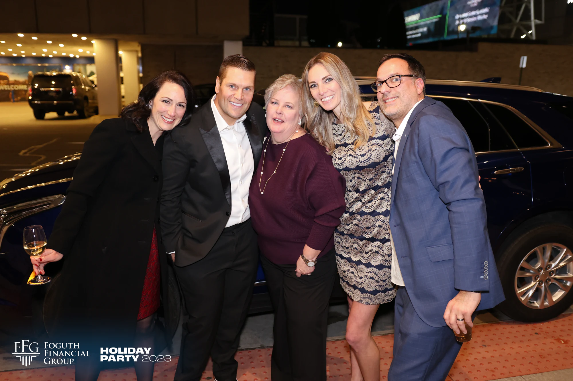 Five guests in black tie leaning in together outside the Foguth Financial holiday party at the Detroit Foundation Hotel