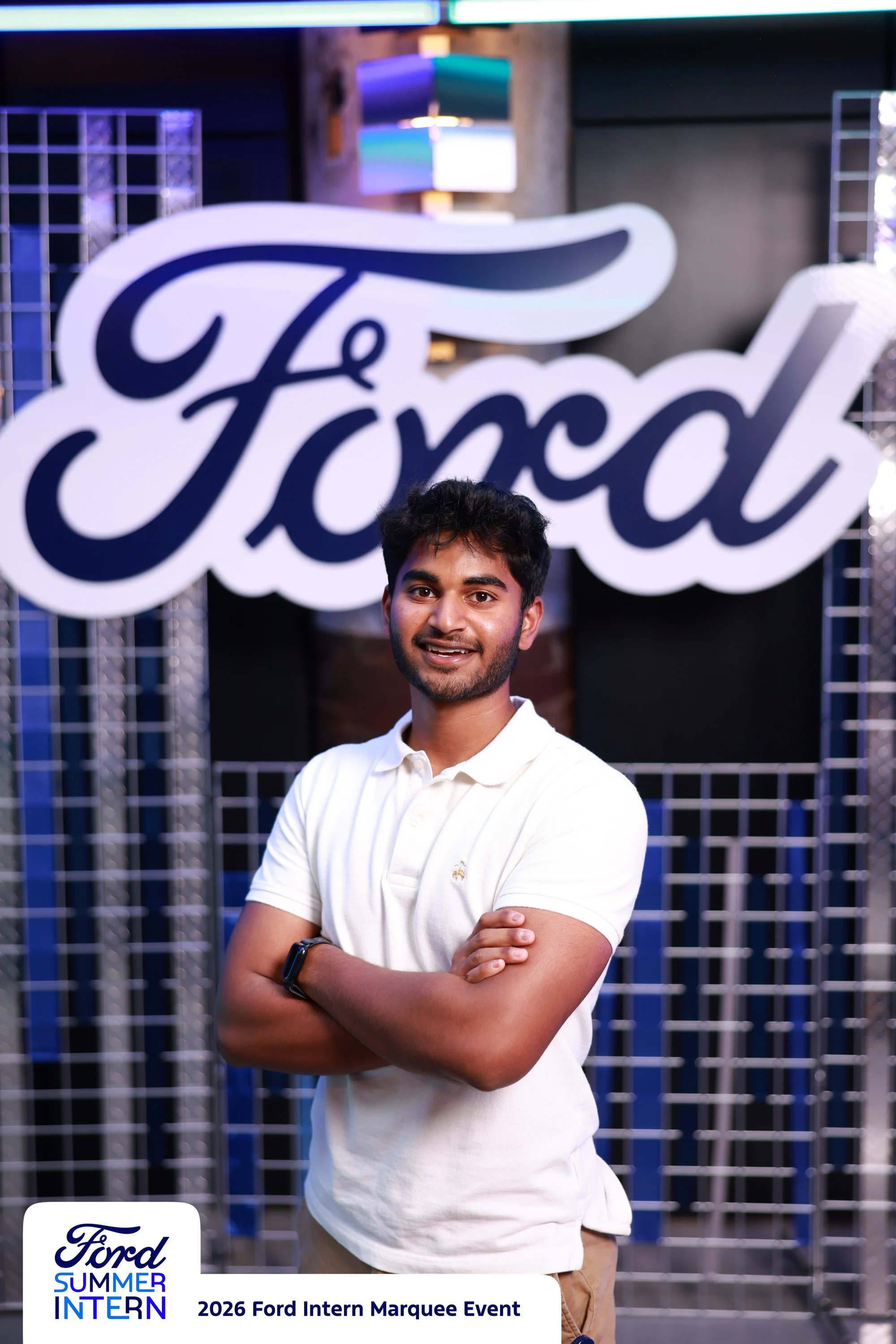 An intern in a white polo, arms crossed, at the Ford Intern Marquee Event