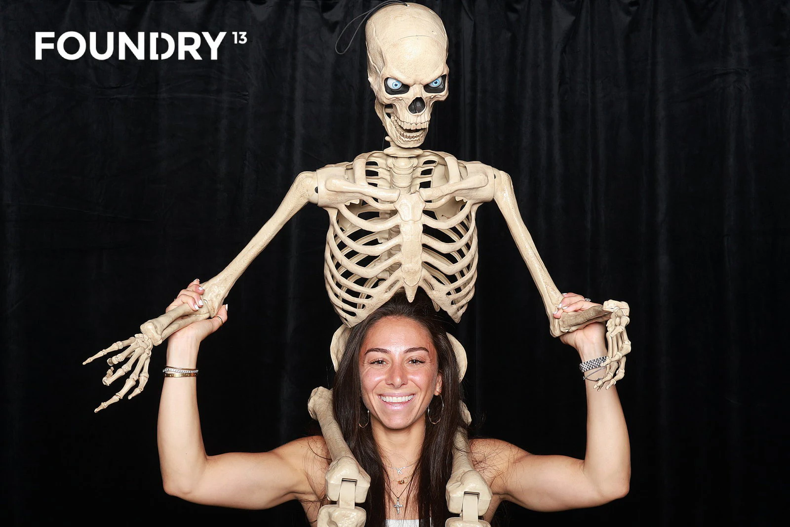 A guest flexing with a skeleton prop draped over her shoulders at Foundry 13
