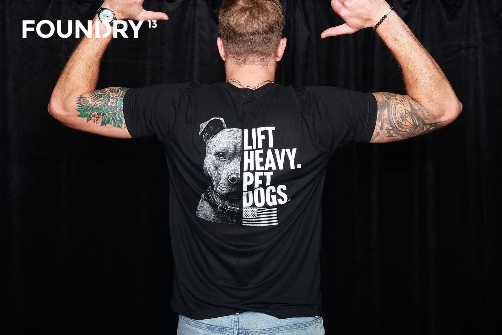 A guest flexing with his back to the camera in a LIFT HEAVY. PET DOGS shirt at Foundry 13
