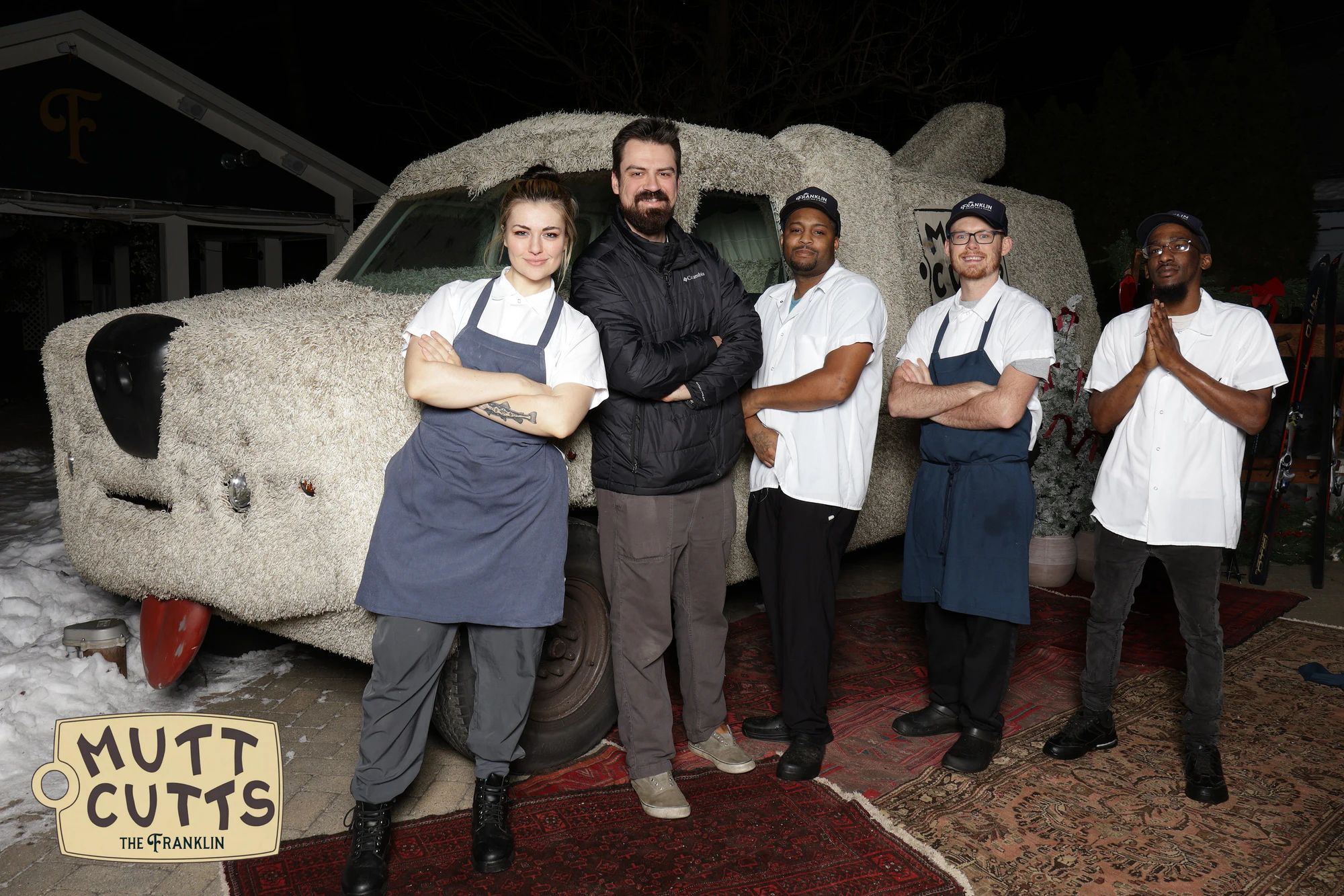 Five of the kitchen crew in chef whites and aprons in front of the Mutt Cutts van at the holiday party at The Franklin