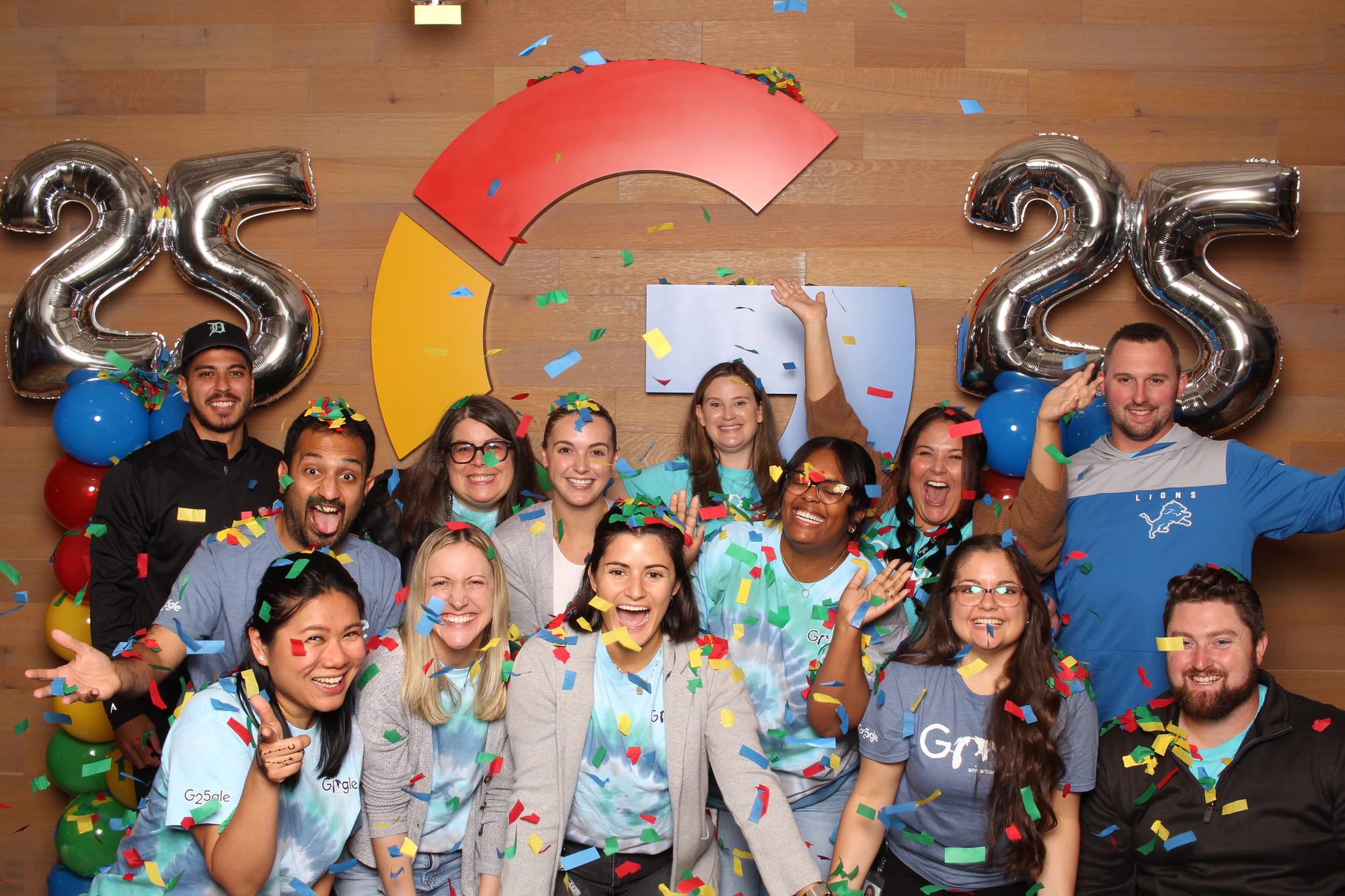 The same team leaning in closer, a man in a cap at the back and a woman in front grinning at Google’s 25th Birthday