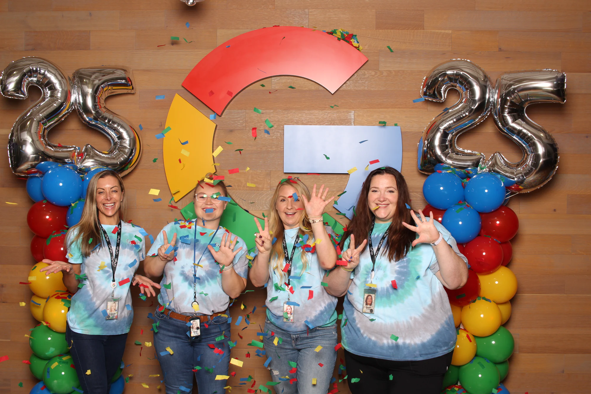 Four women with lanyards waving at the camera at Google’s 25th Birthday