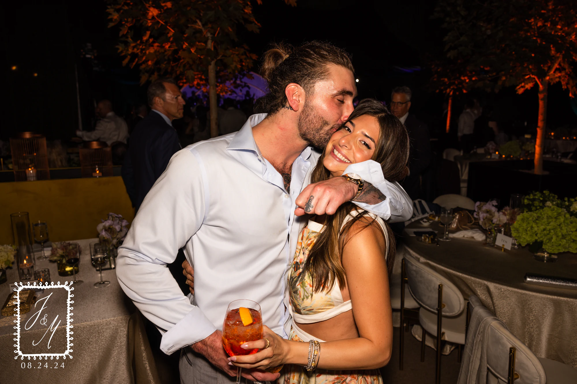 A guest kissing a friend on the top of her head, a cocktail in her hand at Jaclyn + Michael at Franklin Hills Country Club
