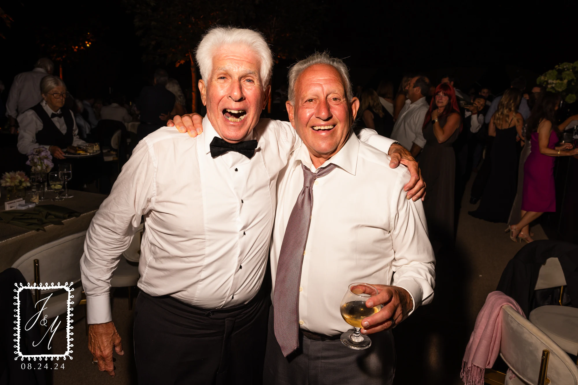 Two guests in white shirts, arms around each other, one mid-laugh at Jaclyn + Michael at Franklin Hills Country Club
