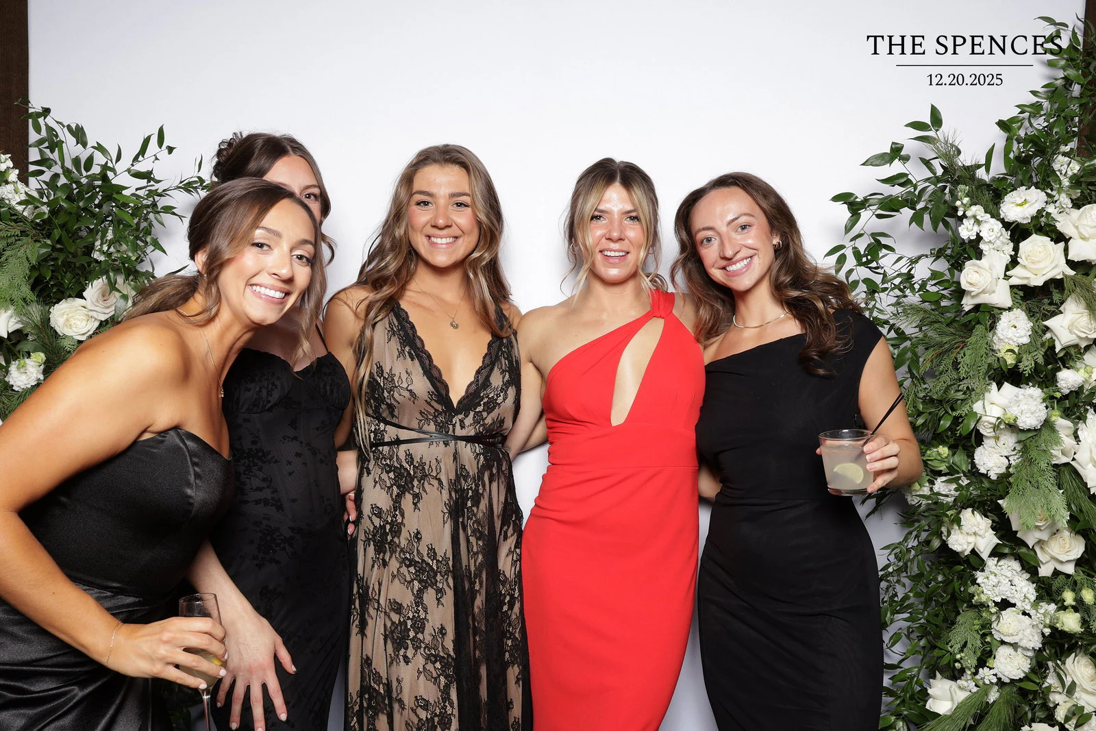 Five women leaning together, one in a red dress and one peeking over a friend’s shoulder at Jessica + Rory