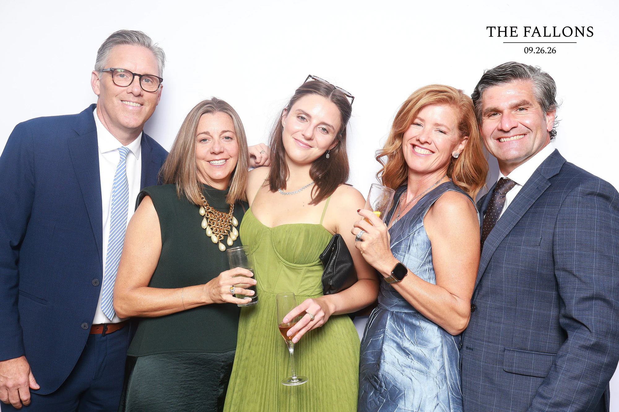 Five guests standing close, a woman in a green dress in the middle holding a drink at Julia + Adam