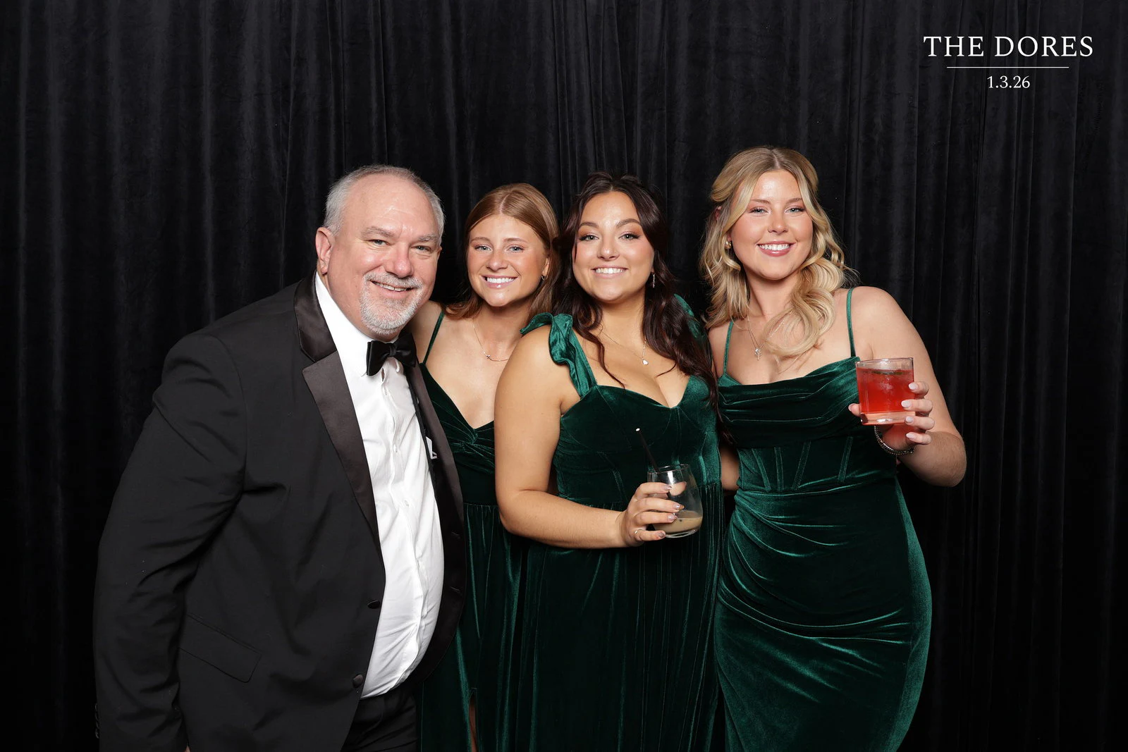 A man in a black tuxedo with three women in emerald velvet gowns at Larkin + Mitchell