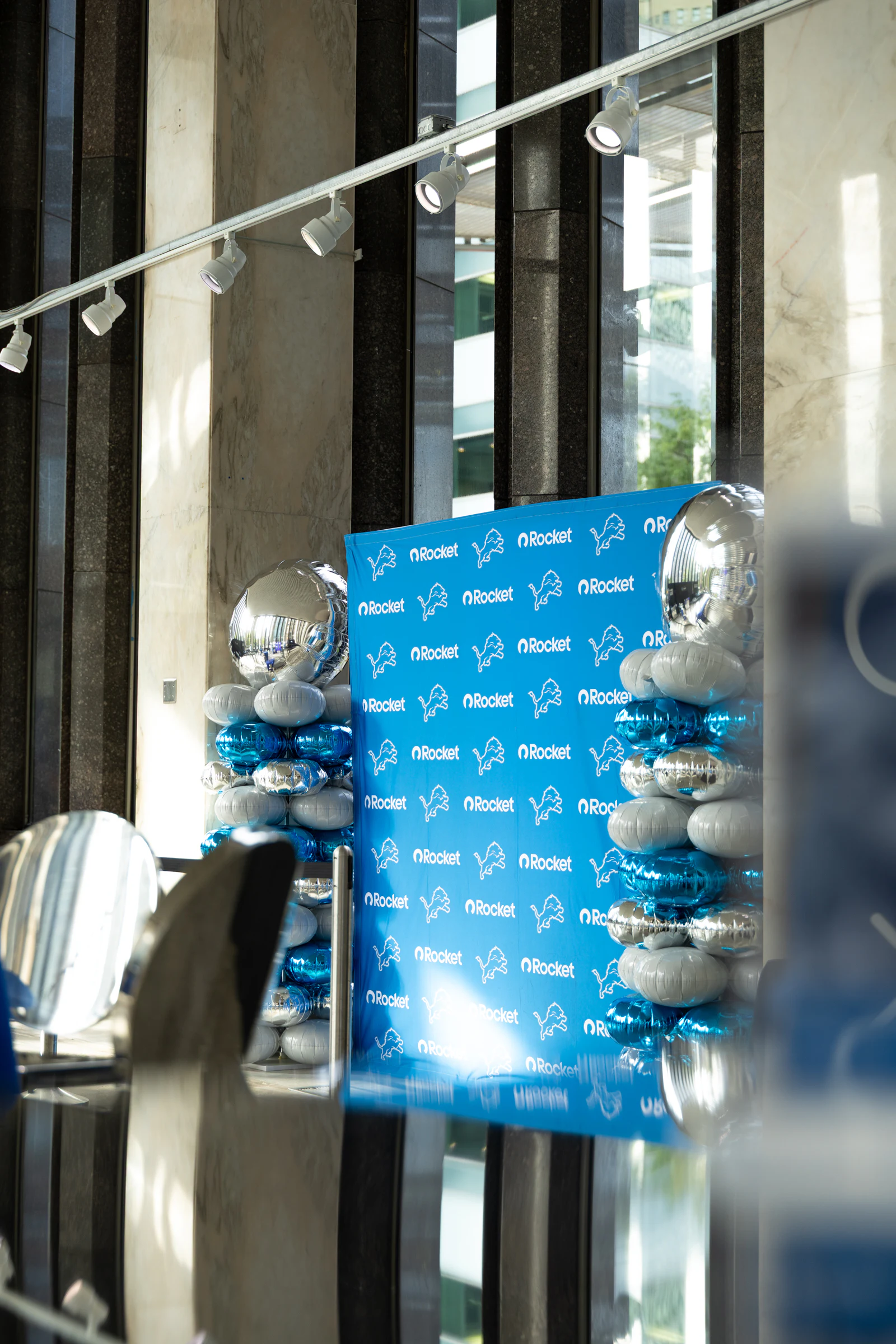 A blue Rocket and Lions step-and-repeat framed by towers of silver and blue balloons under track lighting