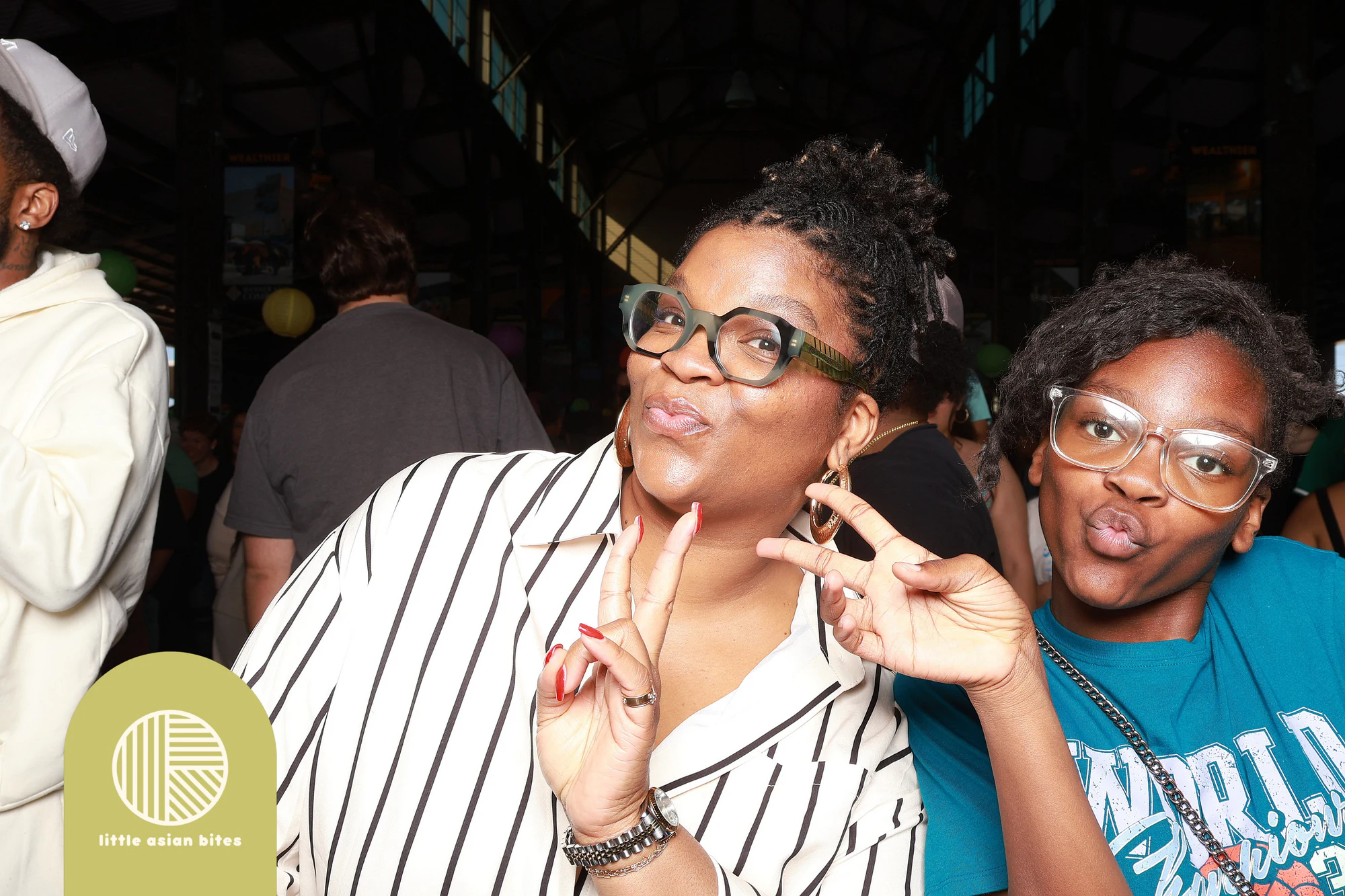 Two guests, glasses and a peace sign, laughing together at Little Asian Bites Night Market