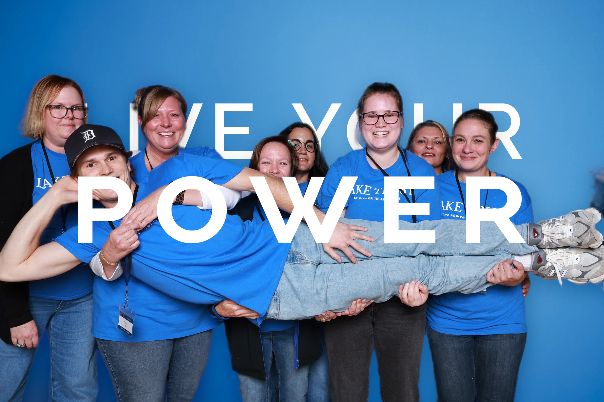 The eight guests holding their friend up a little higher, all smiling at Live Your Power