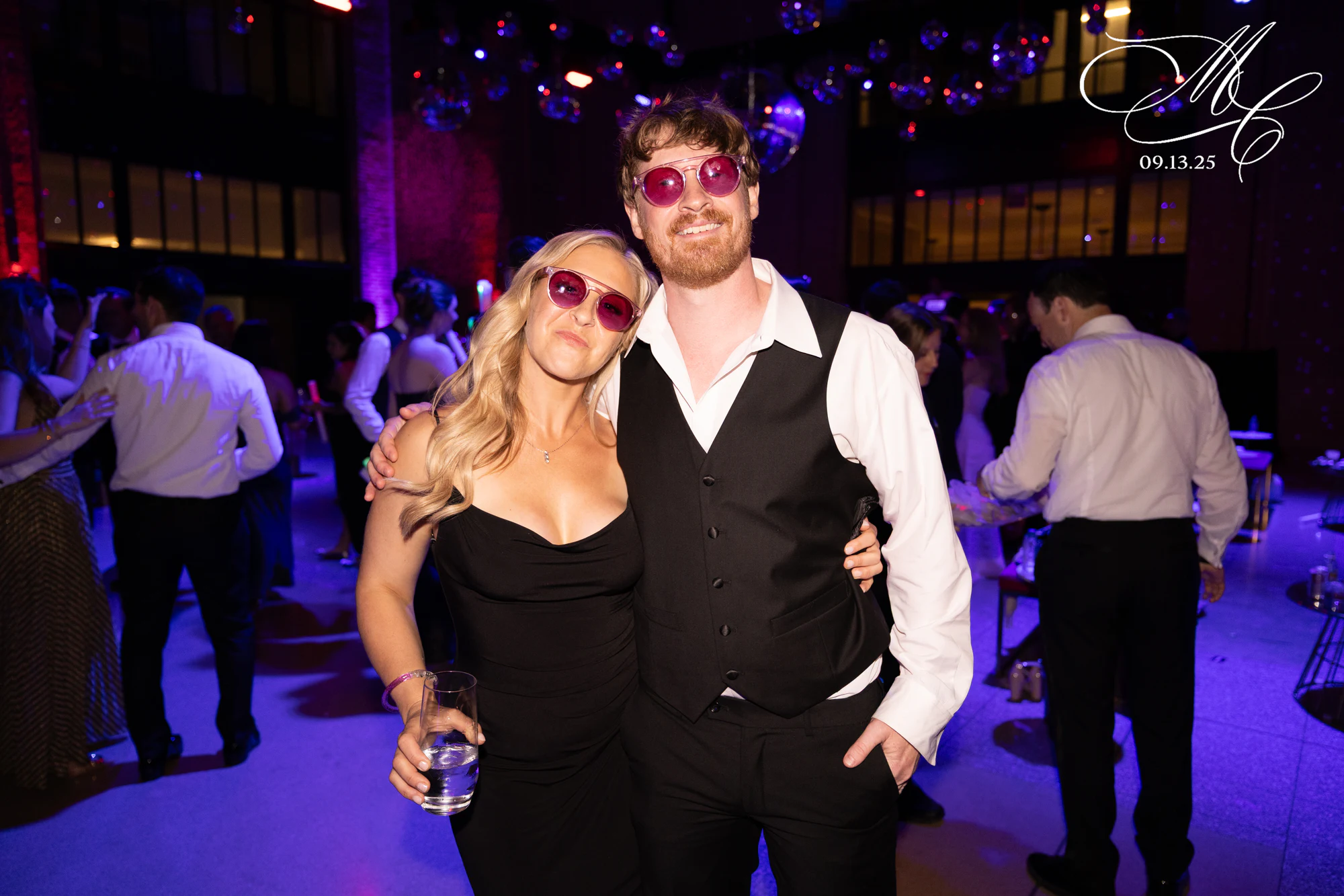 Two guests in party glasses, arms around each other at Madison + Charlie at Michigan Central