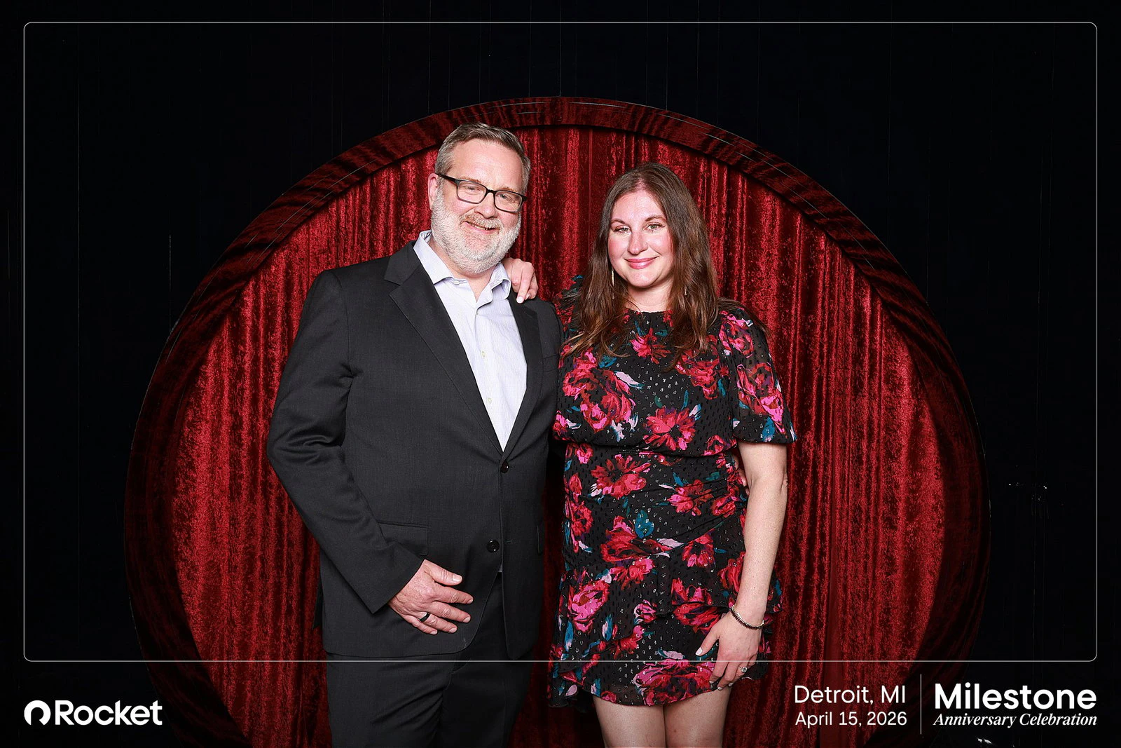 A man in a dark suit and glasses and a woman in a pink and black floral dress at Milestone Anniversary Celebration