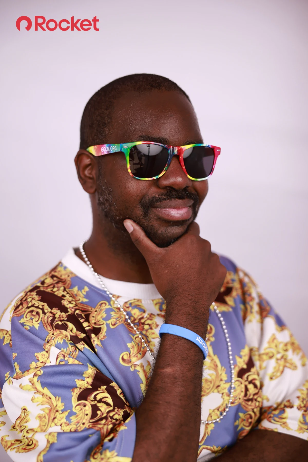 A guest in rainbow sunglasses, hand on chin at My Chosen Family Portraits at Motor City Pride