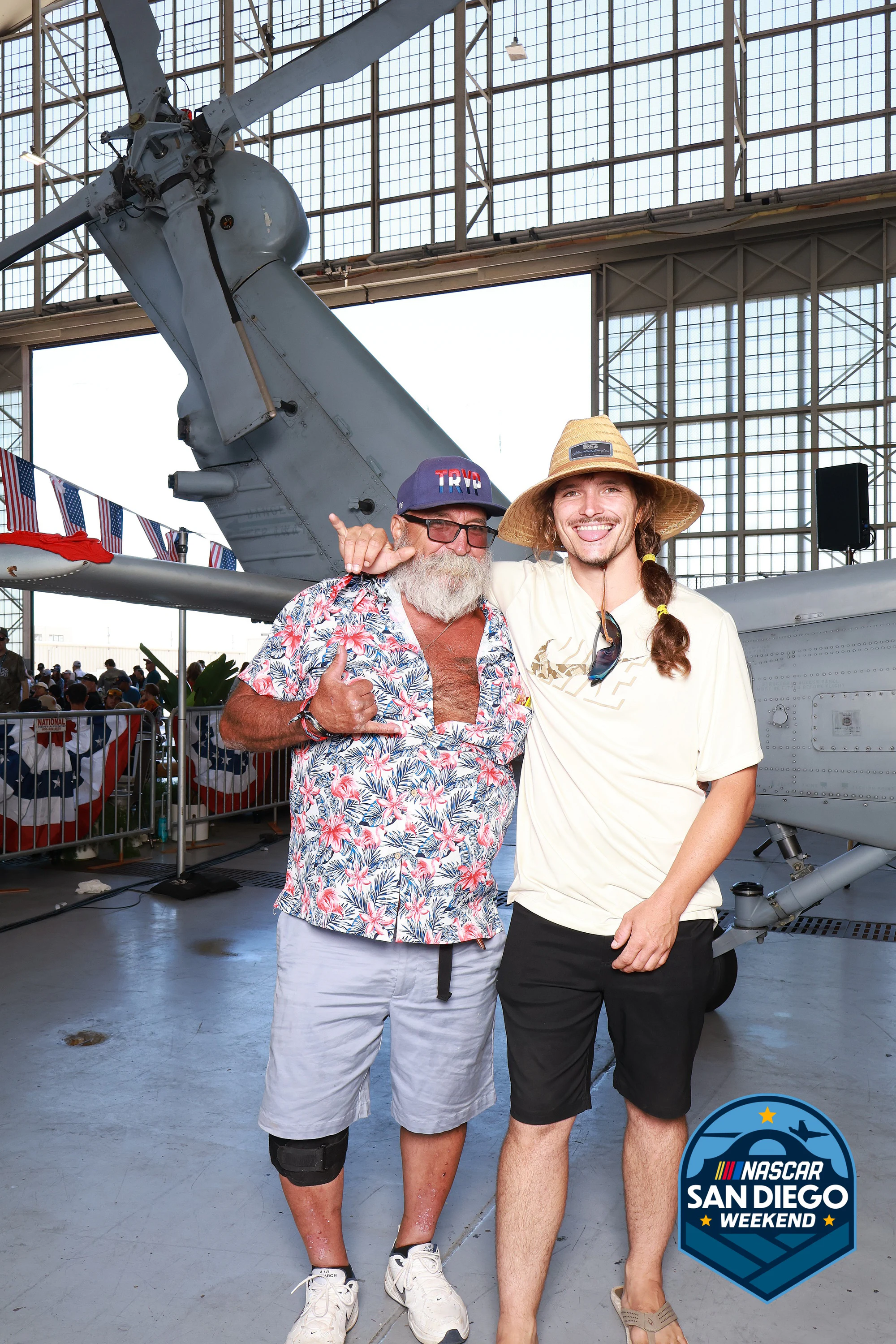 Two guests in a floral shirt and a straw hat at NASCAR San Diego