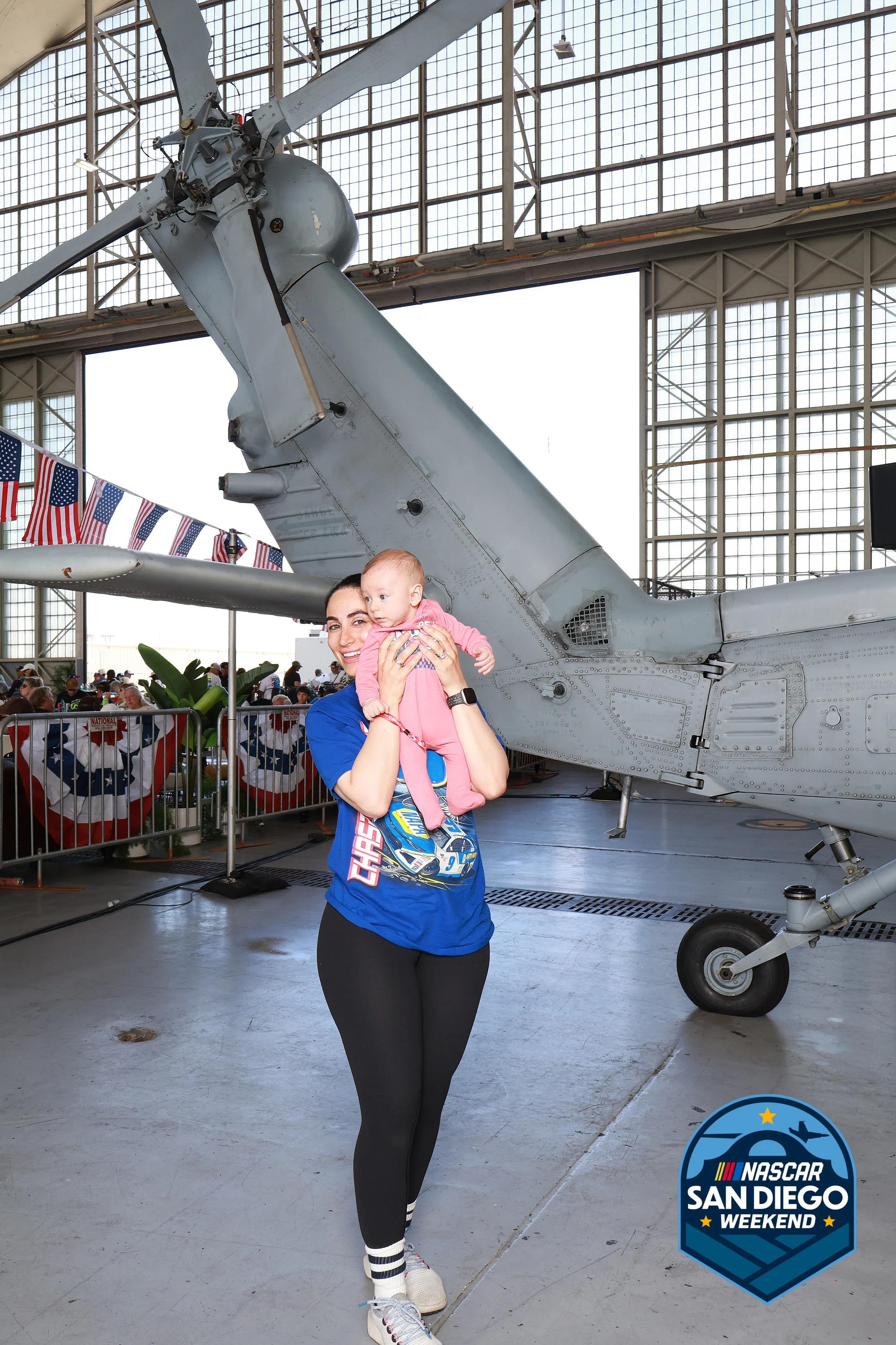 Baby held up to the camera, both parents smiling at NASCAR San Diego