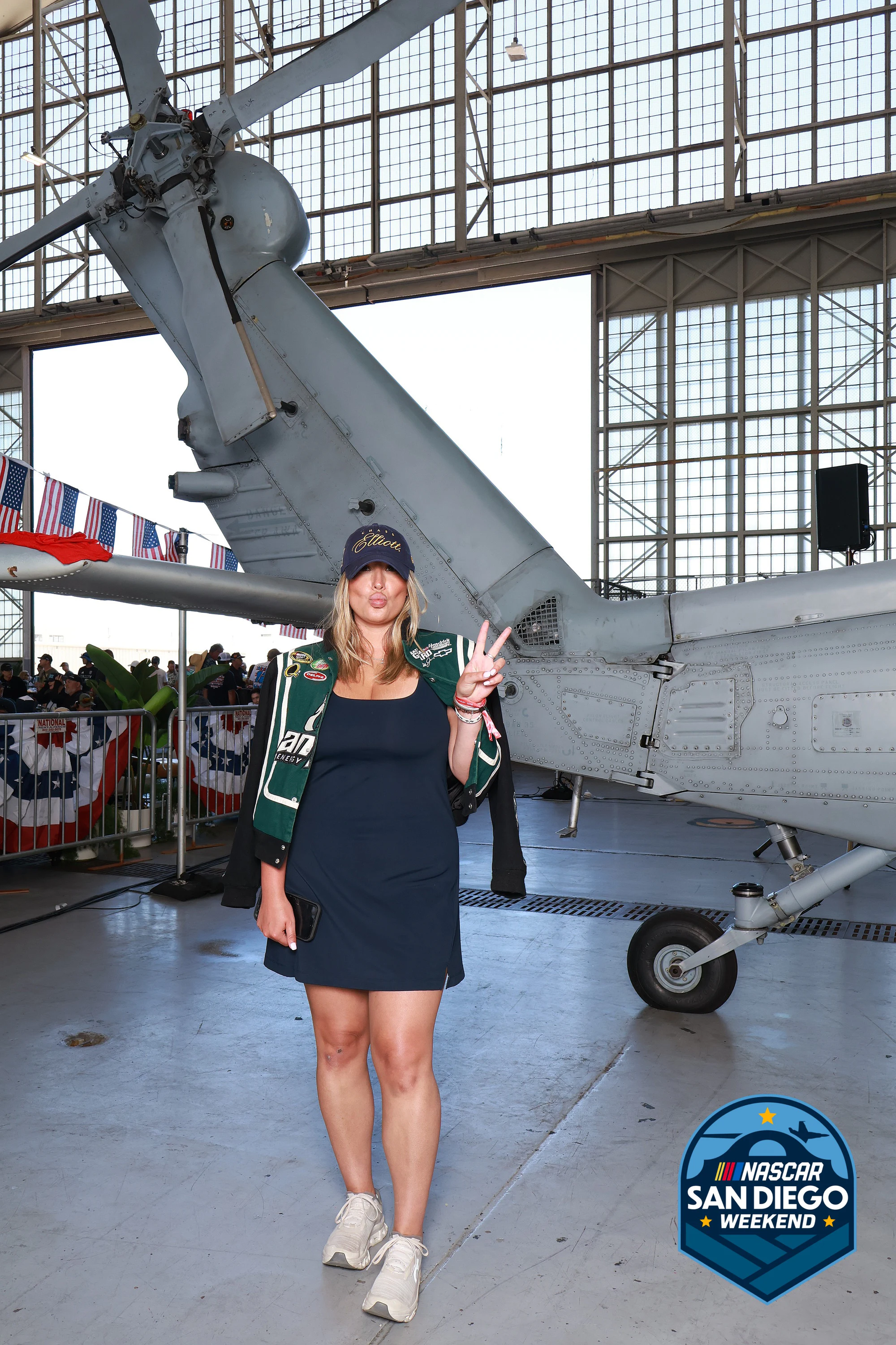 A woman in a cap throwing a peace sign at NASCAR San Diego