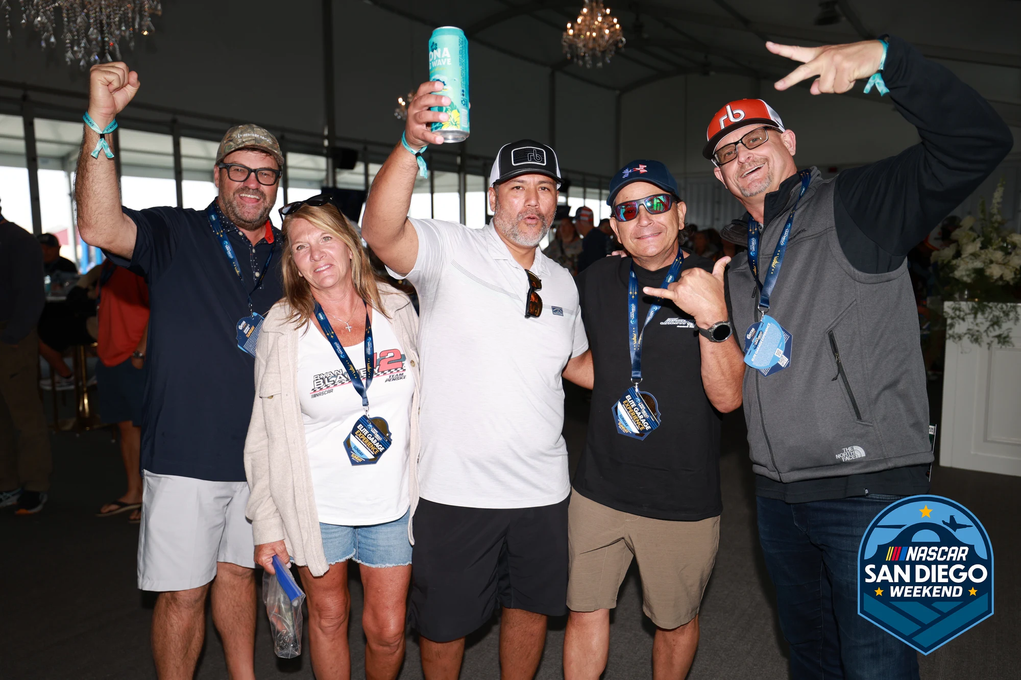 Group with drinks up and arms out, mid-toast at NASCAR San Diego