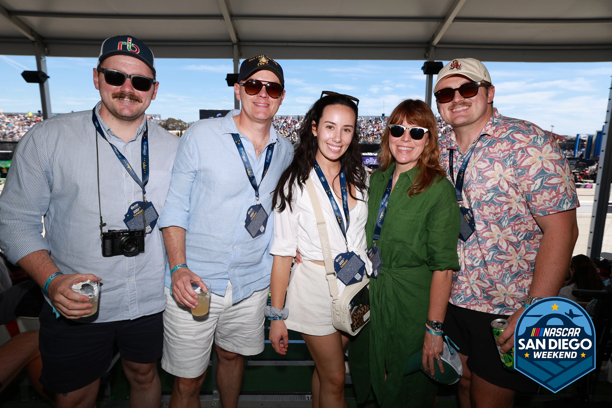 Five friends on the sunny terrace, grandstand behind at NASCAR San Diego