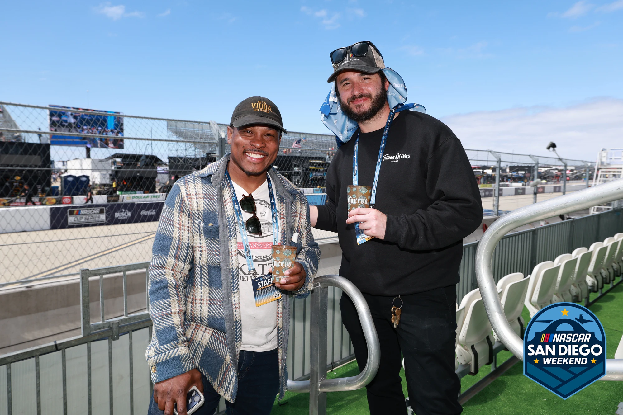 Two guests at the rail under open blue sky at NASCAR San Diego