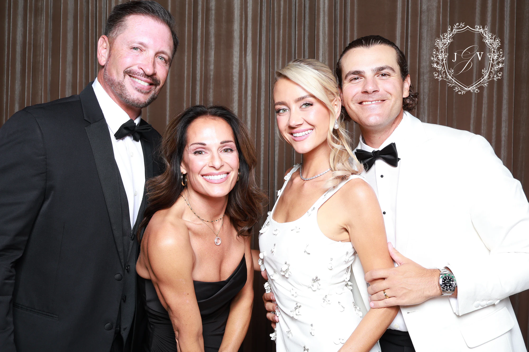 Two couples, the men in a black tuxedo and a white dinner jacket, arm in arm at Nash Gaurino Wedding