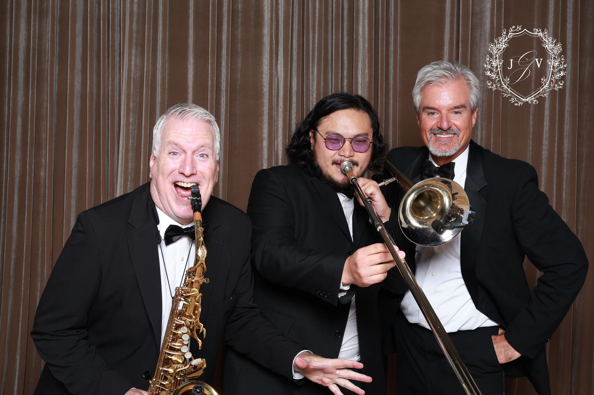 Three men in tuxedos, two of them holding a saxophone and a trombone at Nash Gaurino Wedding